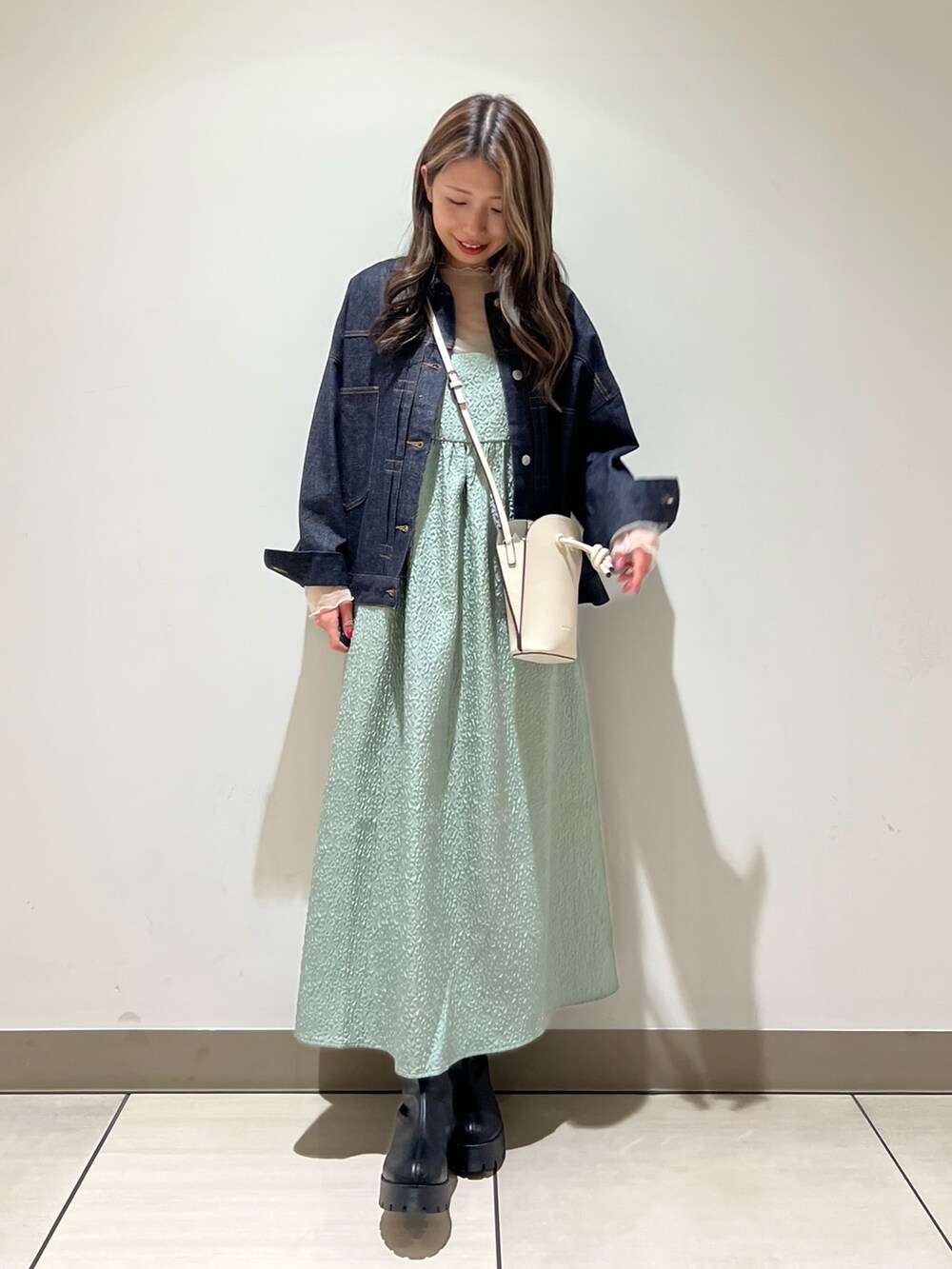 グリーン系のワンピース、ブラック系のブーツ、ホワイト系のTシャツ/カットソーを着用したレディースの冬コーディネートの2枚目の写真