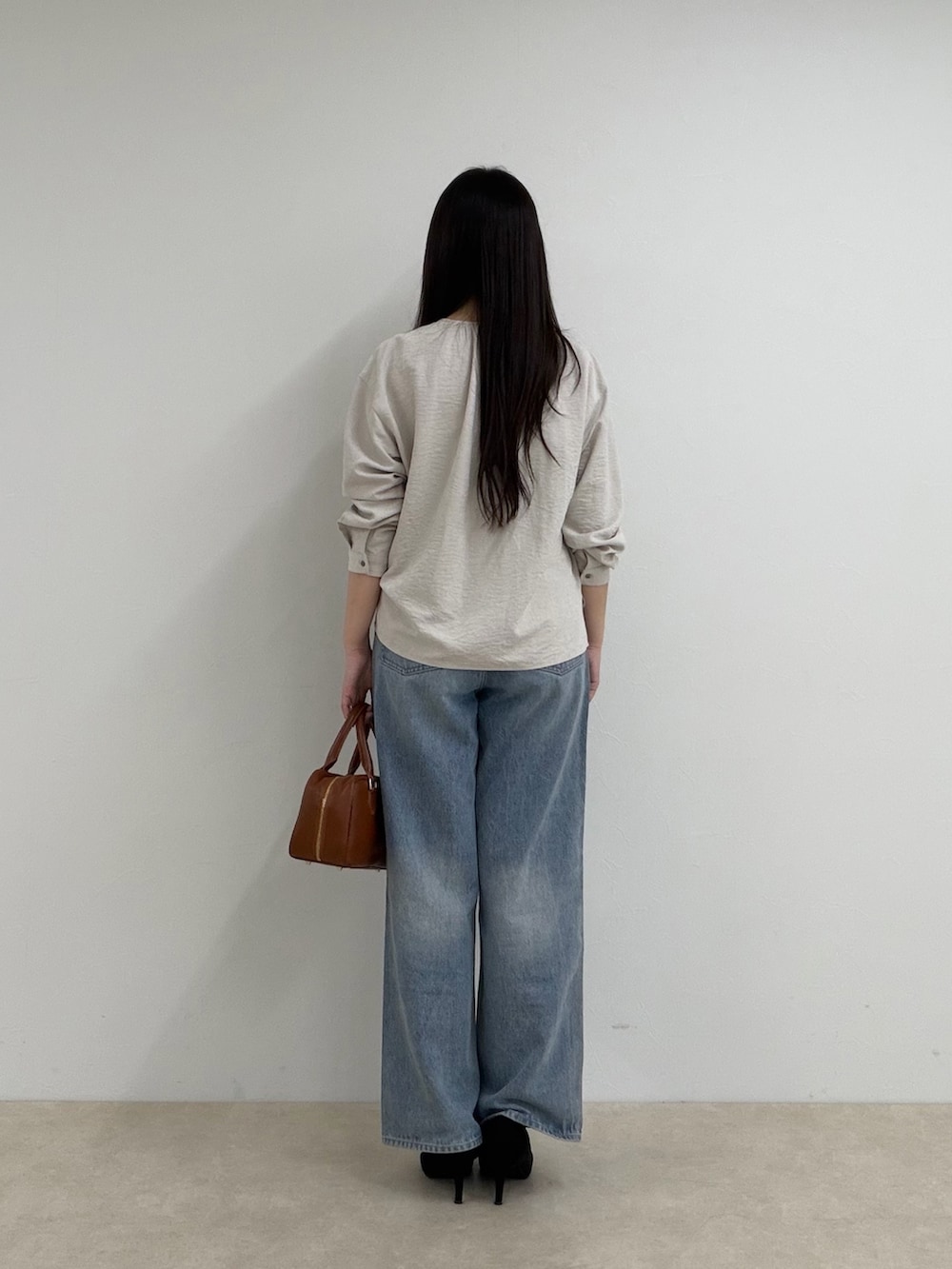 ベージュ系のシャツ/ブラウス、ブルー系のデニムパンツ、ブラック系のボストンバッグを着用したレディースの秋コーディネートの3枚目の写真