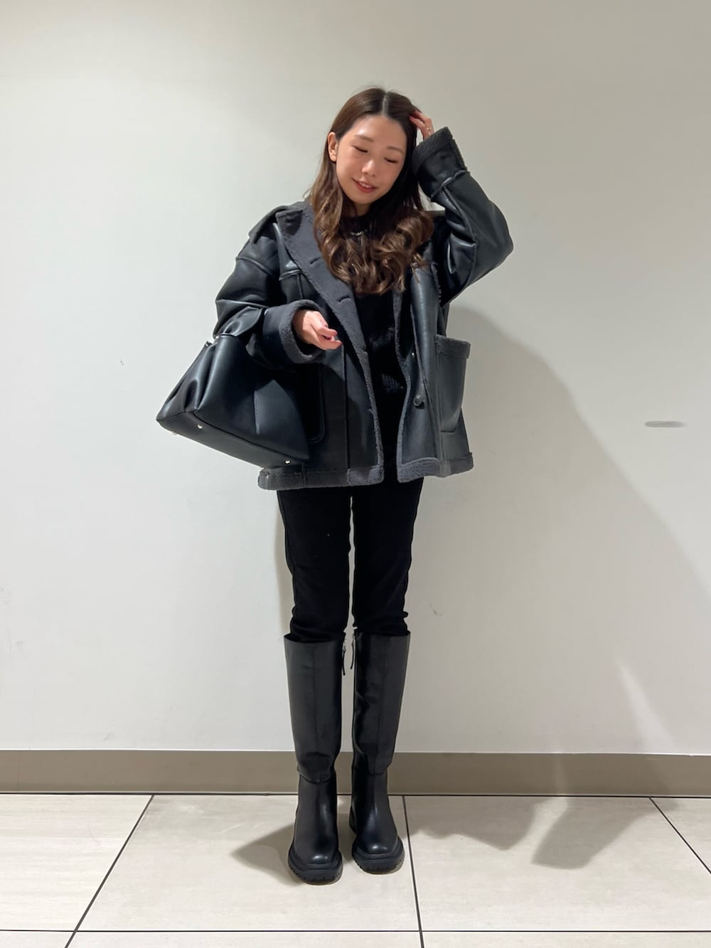 ブラック系のブーツ、ブラック系のデニムパンツ、ブラック系のトートバッグを着用したレディースの冬コーディネートの2枚目の写真