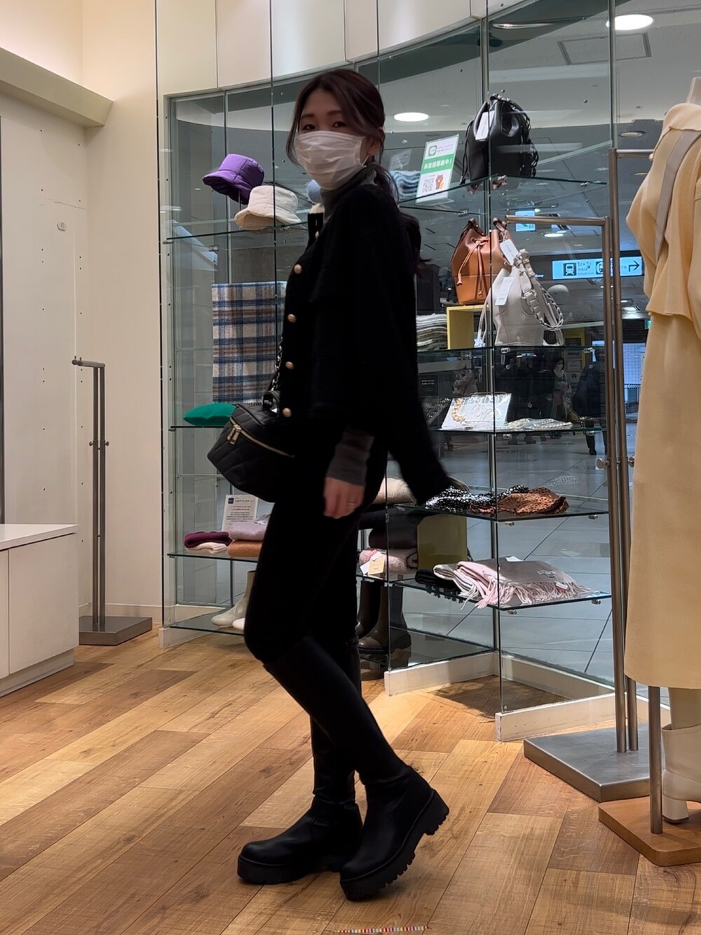 ブラック系のノーカラージャケット、ブラック系のショルダーバッグ、ブラック系のブーツを着用したレディースの冬コーディネートの2枚目の写真