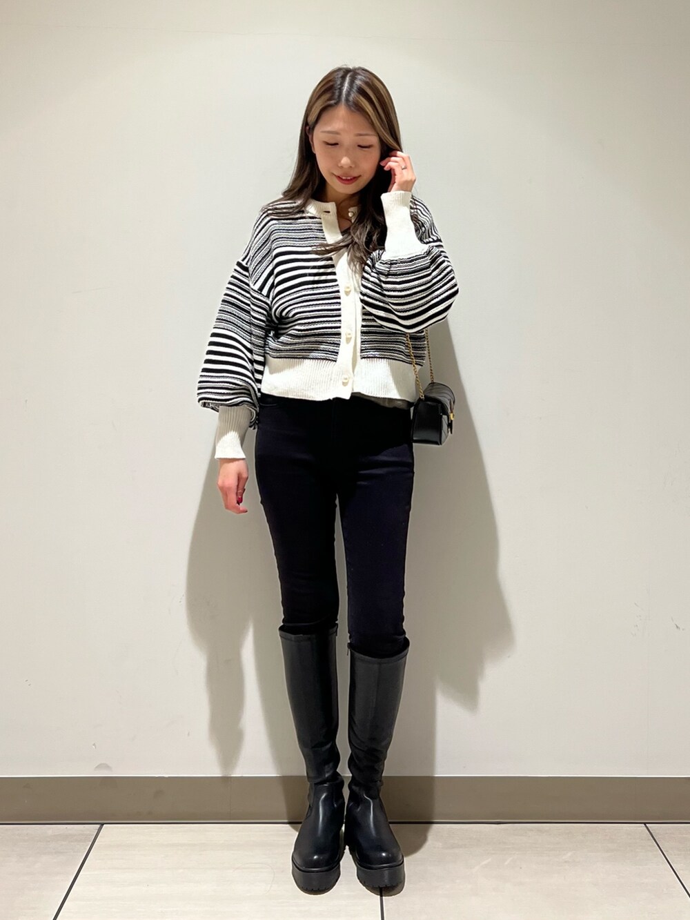 ブラック系のパンツ、ブラック系のショルダーバッグ、ホワイト系のカーディガン/ボレロを着用したレディースの冬コーディネートの2枚目の写真