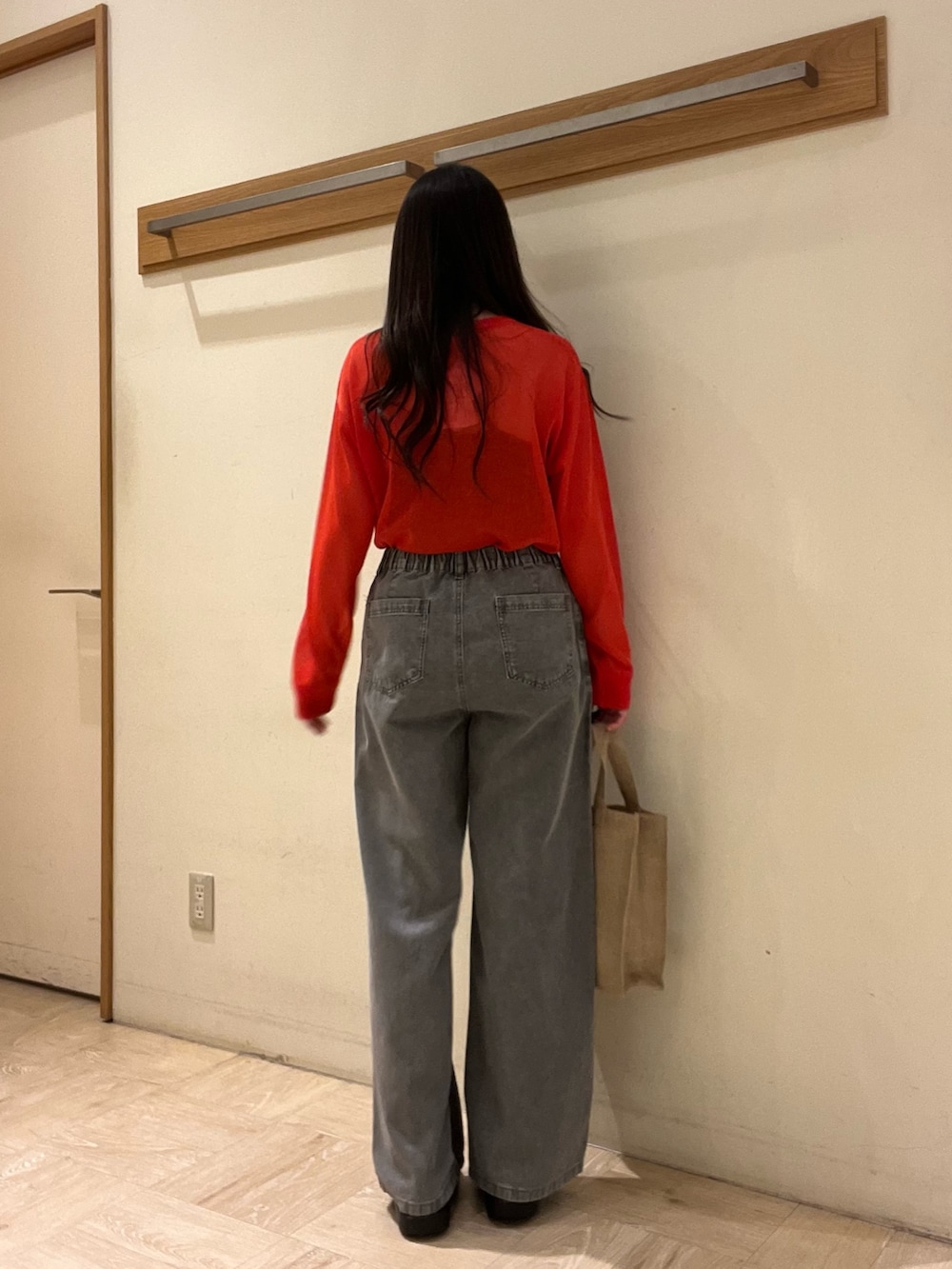 グレー系のデニムパンツ、レッド系のカーディガン/ボレロ、ベージュ系のトートバッグを着用したレディースの春コーディネートの7枚目の写真