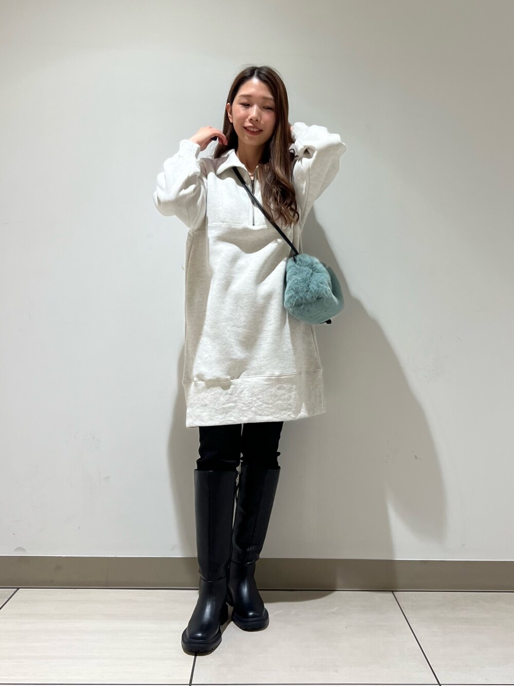 ホワイト系のワンピース、グリーン系のショルダーバッグ、ブラック系のブーツを着用したレディースの冬コーディネートの2枚目の写真