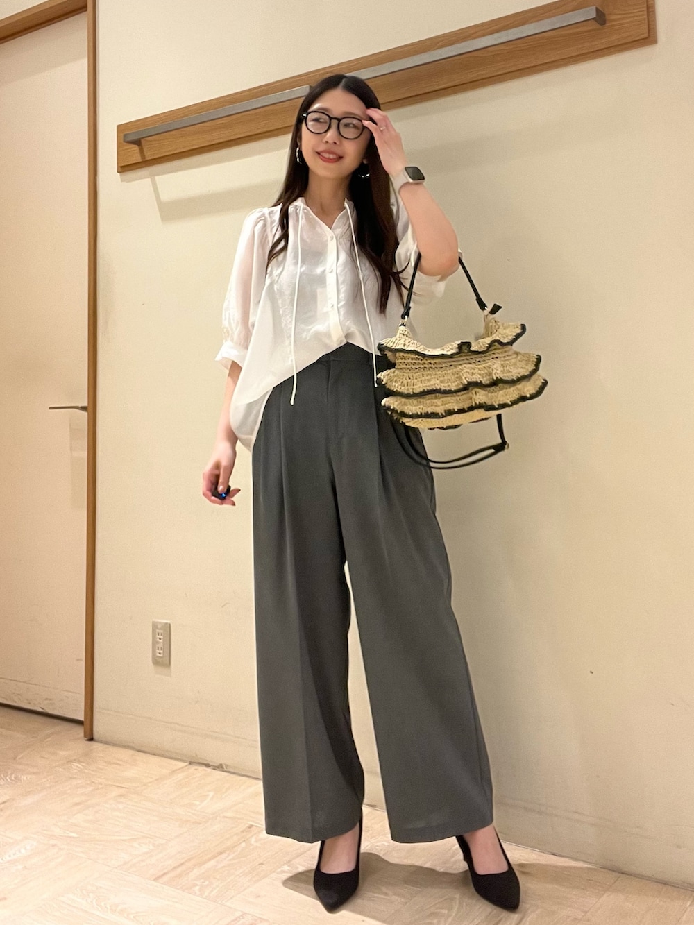 ホワイト系のシャツ/ブラウス、グレー系のスラックス、ブラック系のかごバッグを着用したレディースの夏コーディネートの2枚目の写真