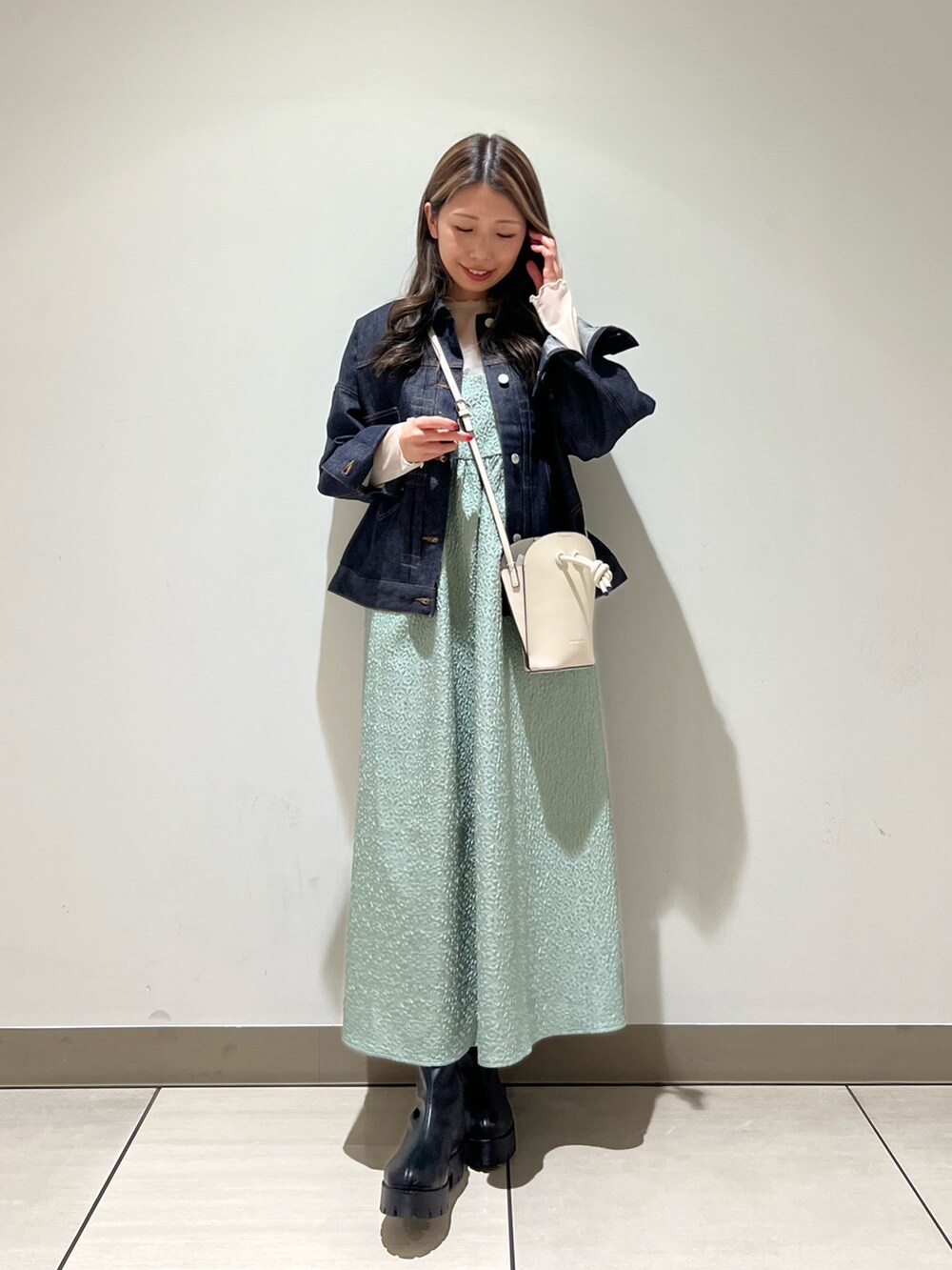 グリーン系のワンピース、ブラック系のブーツ、ホワイト系のTシャツ/カットソーを着用したレディースの冬コーディネートの3枚目の写真