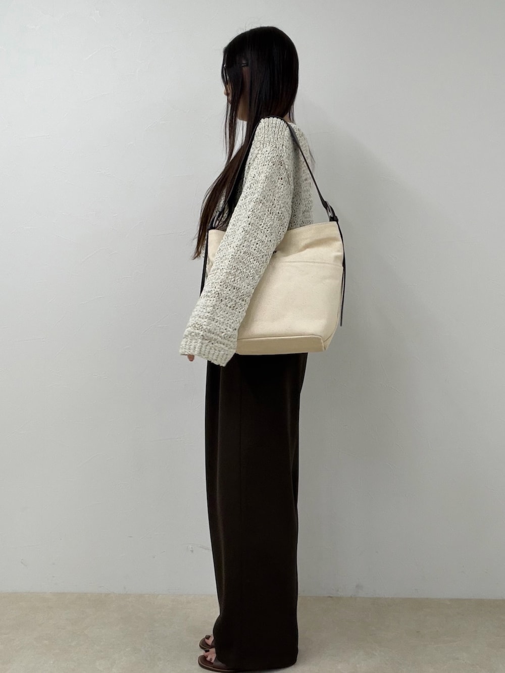 ベージュ系のニット/セーター、ブラウン系のその他パンツ、ホワイト系のショルダーバッグを着用したレディースの春コーディネートの3枚目の写真