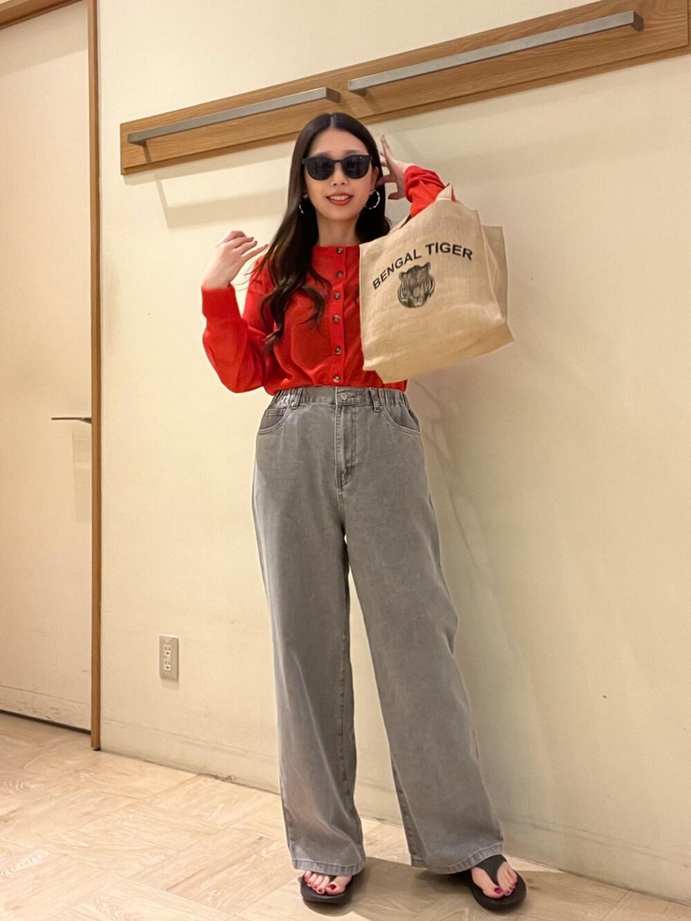 グレー系のデニムパンツ、レッド系のカーディガン/ボレロ、ベージュ系のトートバッグを着用したレディースの春コーディネートの5枚目の写真