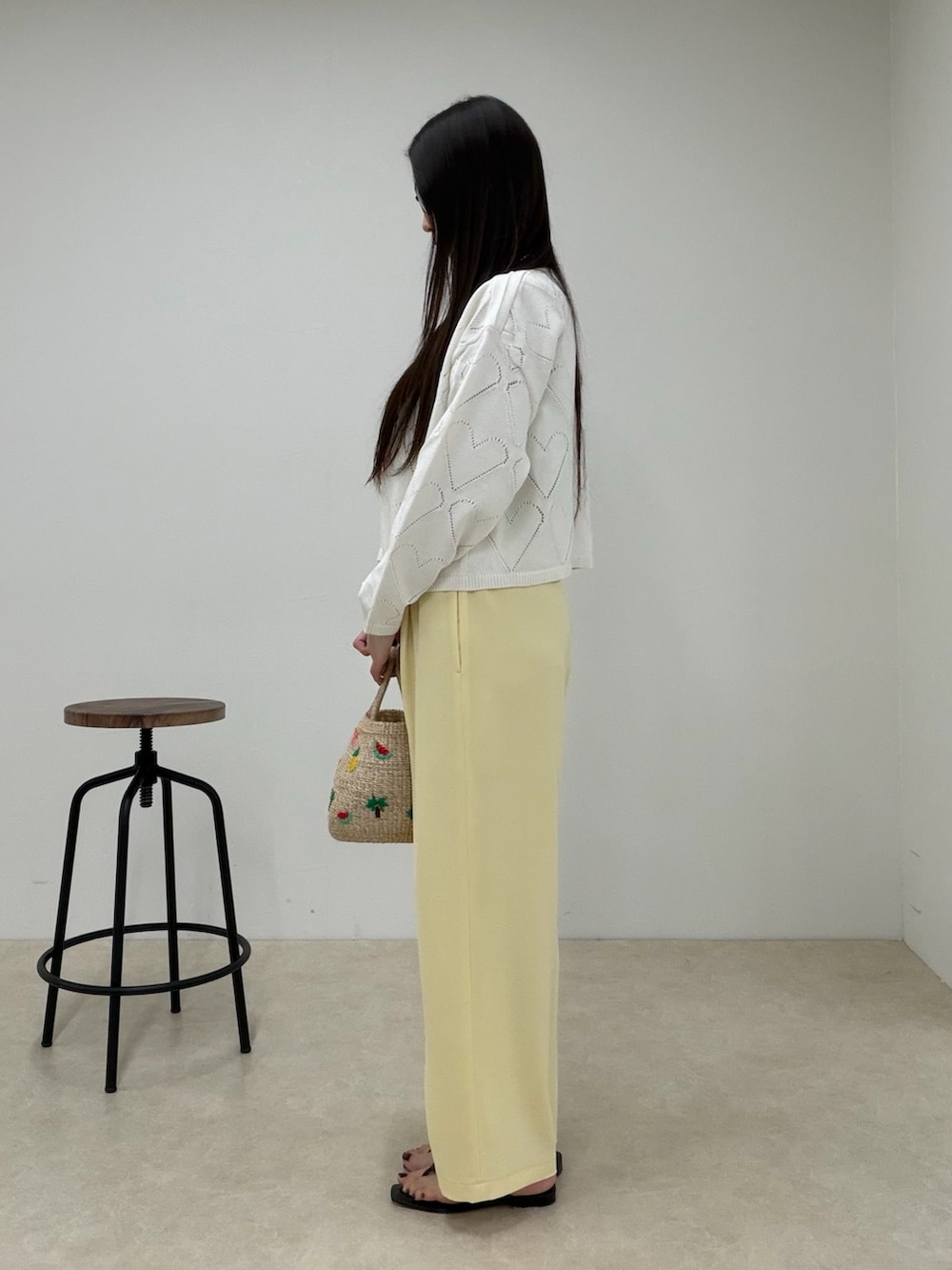 ホワイト系のニット/セーター、イエロー系のその他パンツ、ベージュ系のかごバッグを着用したレディースの春コーディネートの2枚目の写真