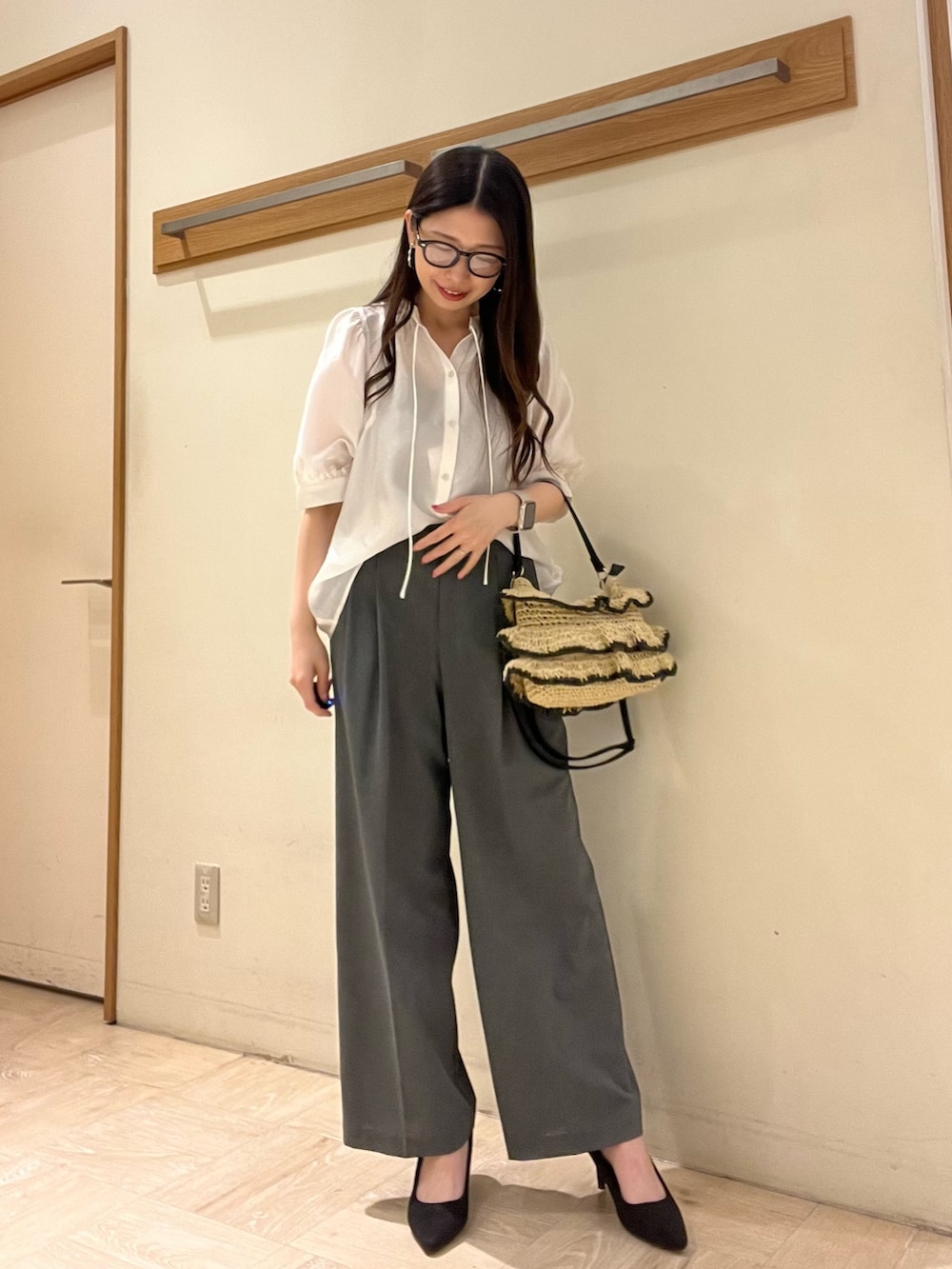 ホワイト系のシャツ/ブラウス、グレー系のスラックス、ブラック系のかごバッグを着用したレディースの夏コーディネートの3枚目の写真
