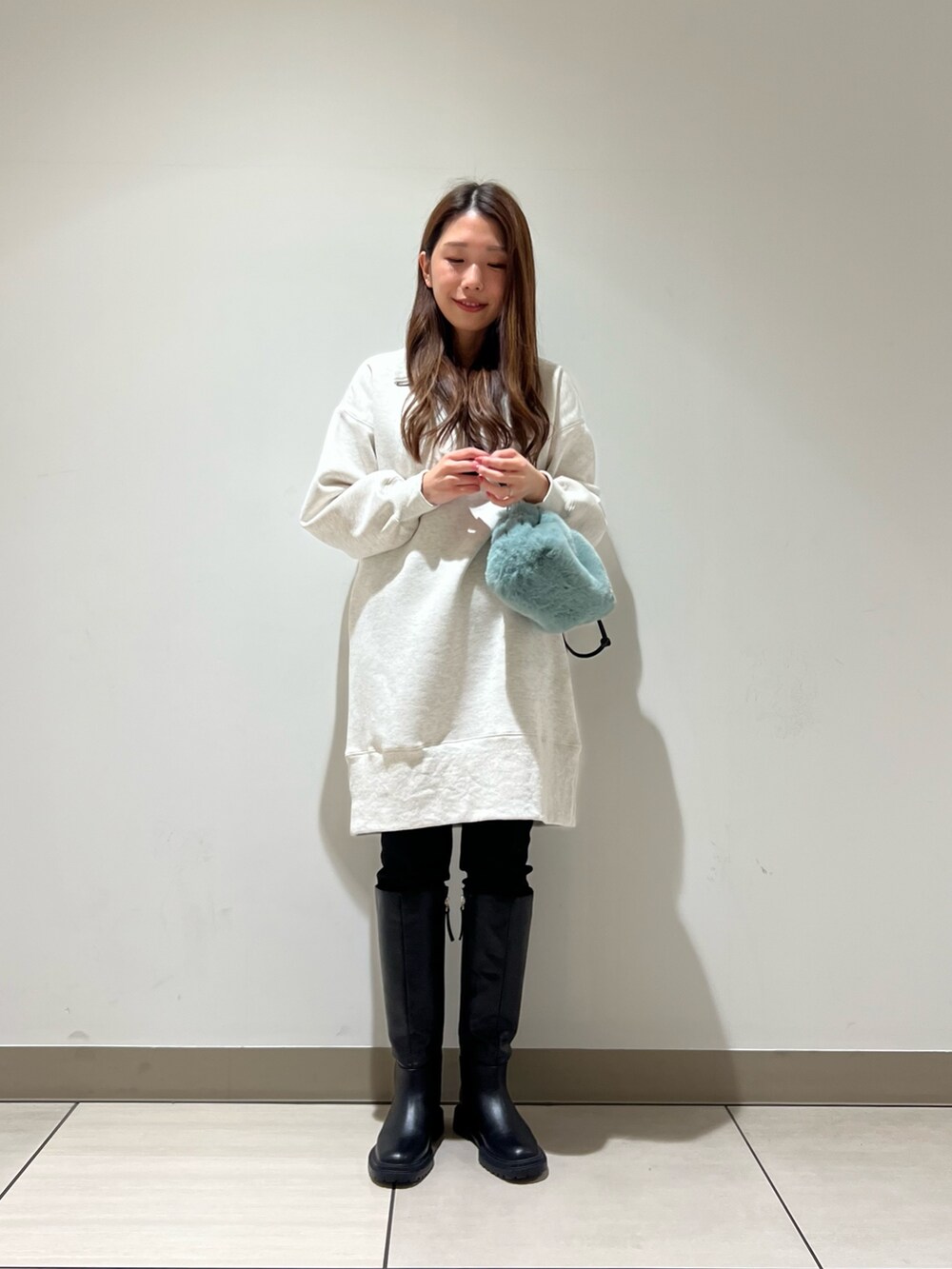 ホワイト系のワンピース、グリーン系のショルダーバッグ、ブラック系のブーツを着用したレディースの冬コーディネートの4枚目の写真