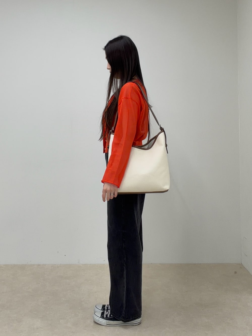 オレンジ系のカーディガン/ボレロ、ホワイト系のショルダーバッグ、ブラック系のデニムパンツを着用したレディースの春コーディネートの2枚目の写真