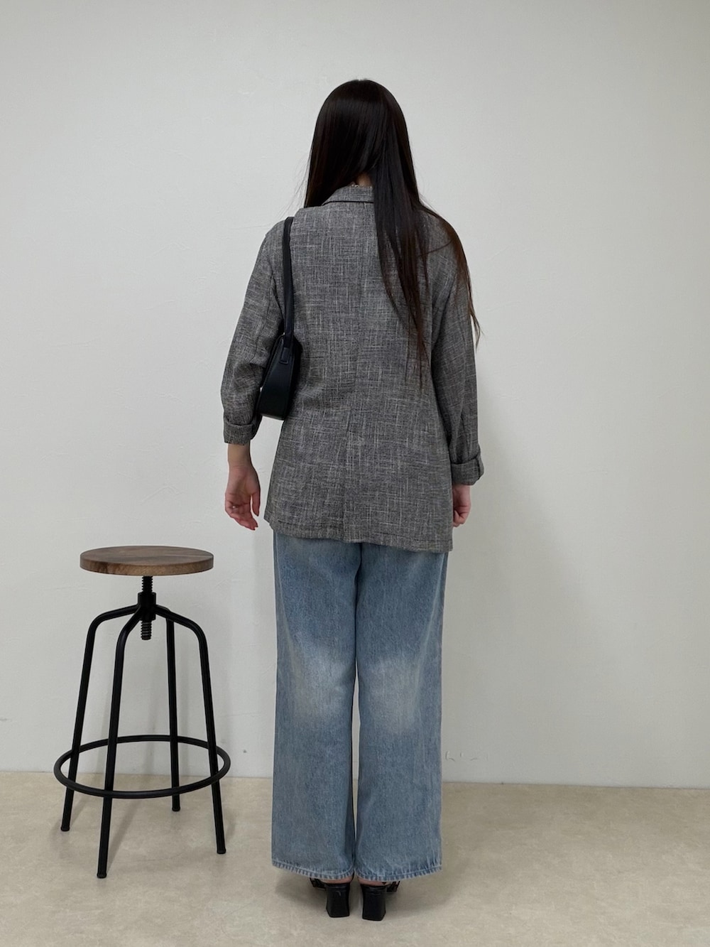 ブルー系のデニムパンツ、ブラック系のテーラードジャケット、グレー系のタンクトップを着用したレディースの春コーディネートの4枚目の写真