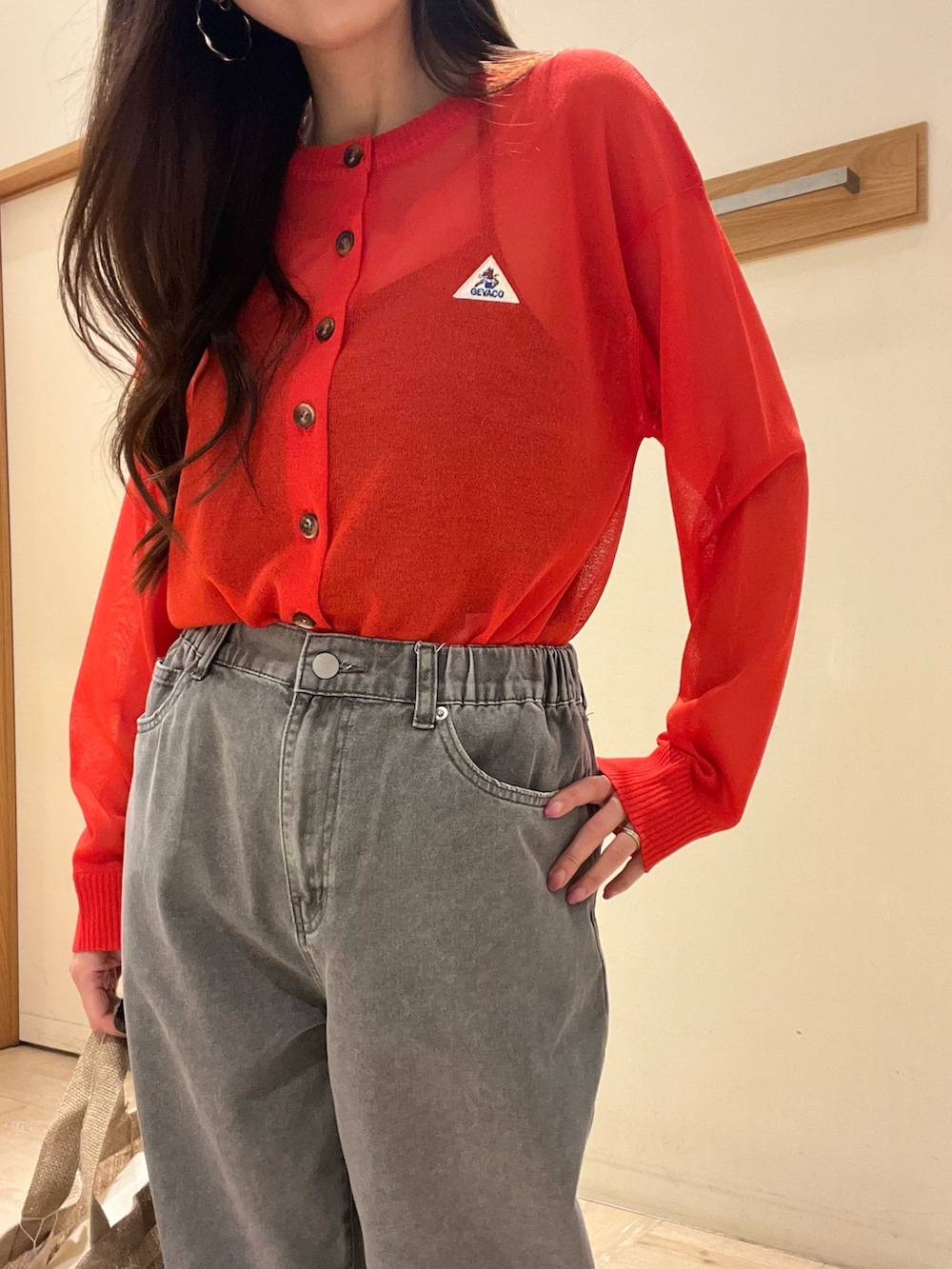 グレー系のデニムパンツ、レッド系のカーディガン/ボレロ、ベージュ系のトートバッグを着用したレディースの春コーディネートの8枚目の写真