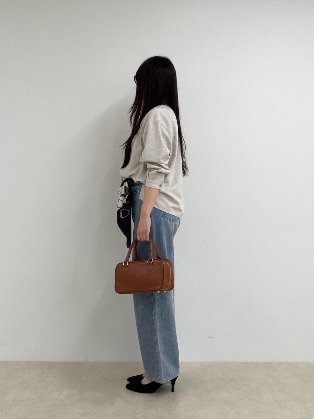 ベージュ系のシャツ/ブラウス、ブルー系のデニムパンツ、ブラック系のボストンバッグを着用したレディースの秋コーディネートの2枚目の写真