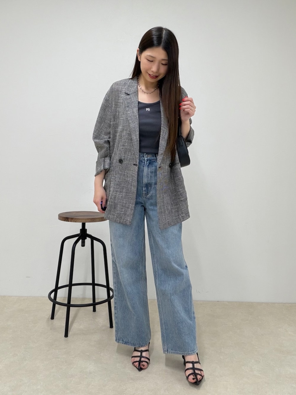 ブルー系のデニムパンツ、ブラック系のテーラードジャケット、グレー系のタンクトップを着用したレディースの春コーディネートの2枚目の写真