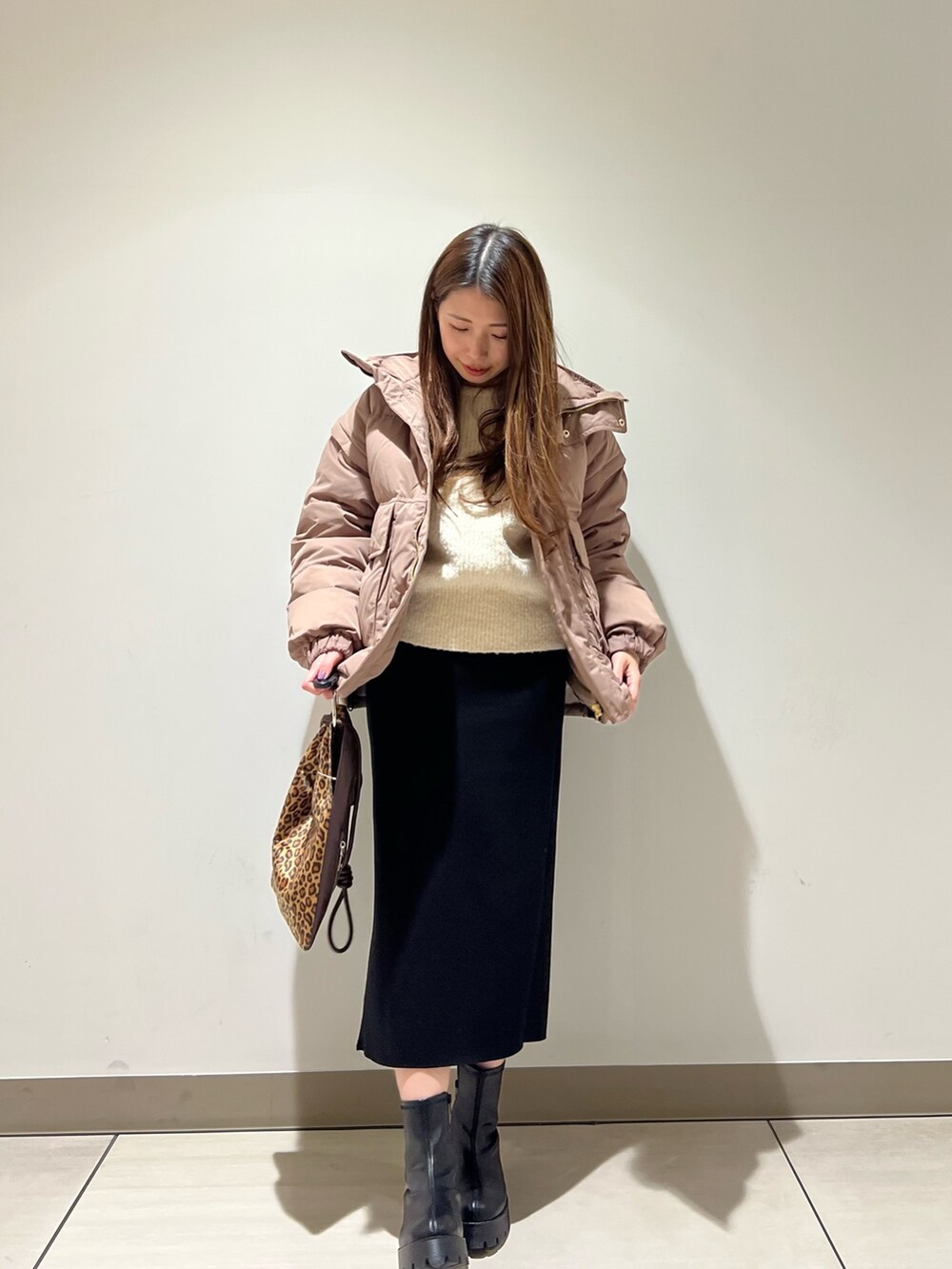 ブラウン系のダウンジャケット/コート、ホワイト系のニット/セーター、ブラック系のスカートを着用したレディースの冬コーディネートの2枚目の写真