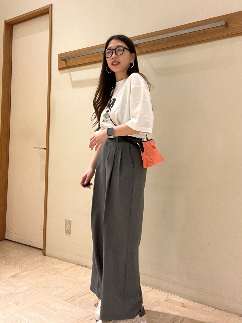 ピンク系のショルダーバッグ、ホワイト系のTシャツ/カットソー、グレー系のスラックスを着用したレディースの夏コーディネートの2枚目の写真