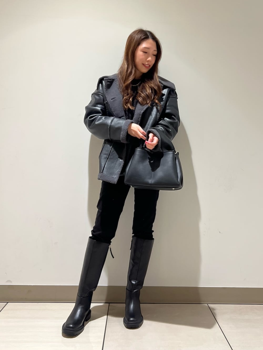 ブラック系のブーツ、ブラック系のデニムパンツ、ブラック系のトートバッグを着用したレディースの冬コーディネートの3枚目の写真