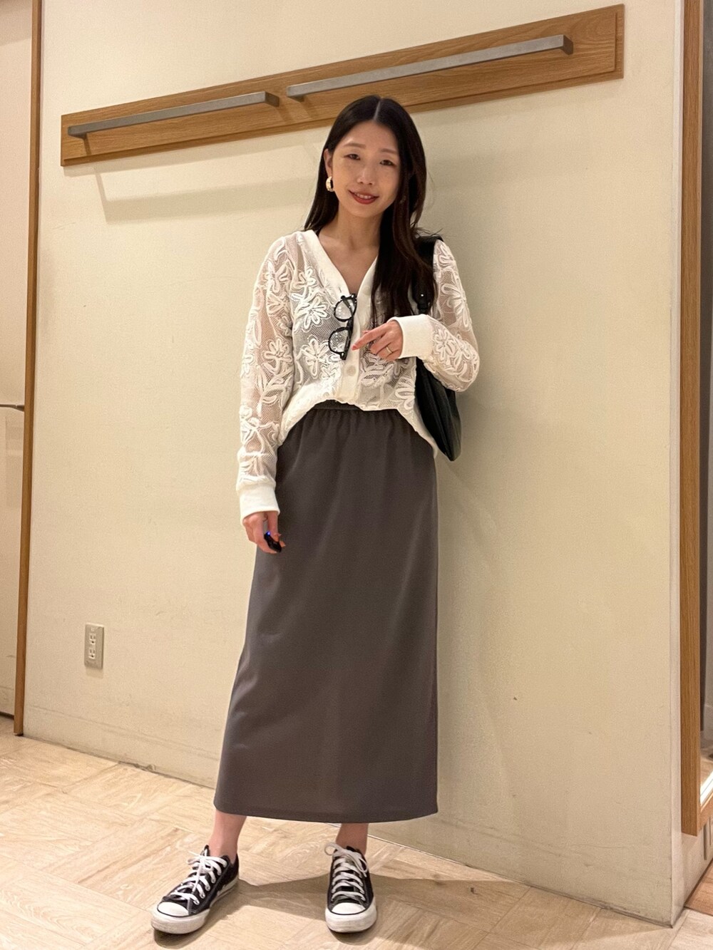 グレー系のスカート、ホワイト系のカーディガン/ボレロ、ブラック系のショルダーバッグを着用したレディースの春コーディネートの2枚目の写真