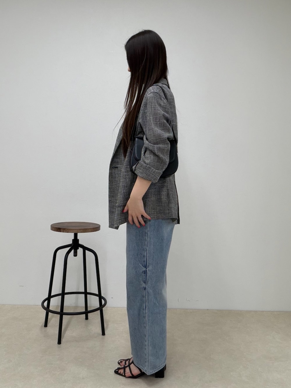 ブルー系のデニムパンツ、ブラック系のテーラードジャケット、グレー系のタンクトップを着用したレディースの春コーディネートの3枚目の写真