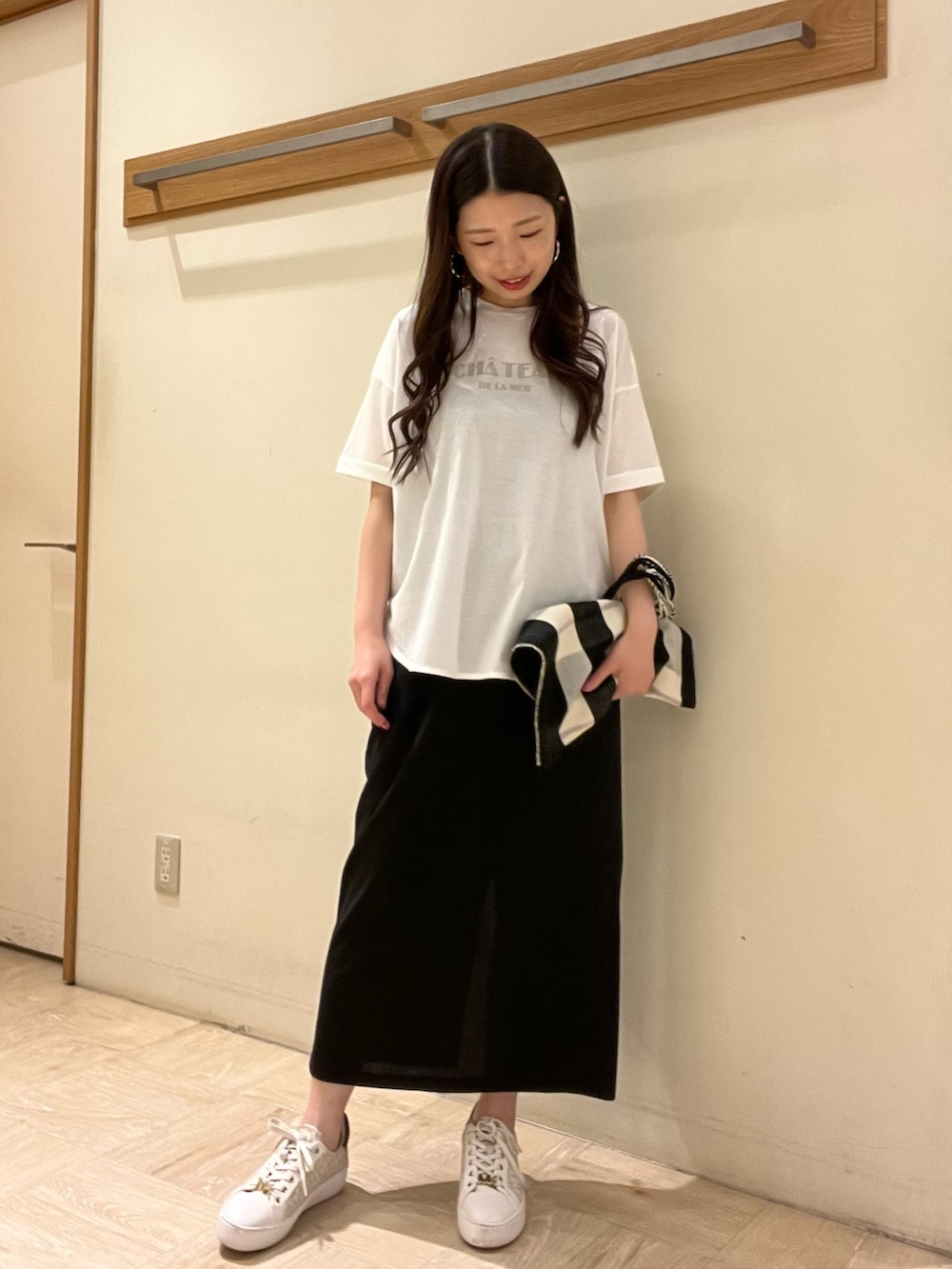 ホワイト系のTシャツ/カットソー、ブラック系のトートバッグ、ブラック系のスカートを着用したレディースの夏コーディネートの2枚目の写真