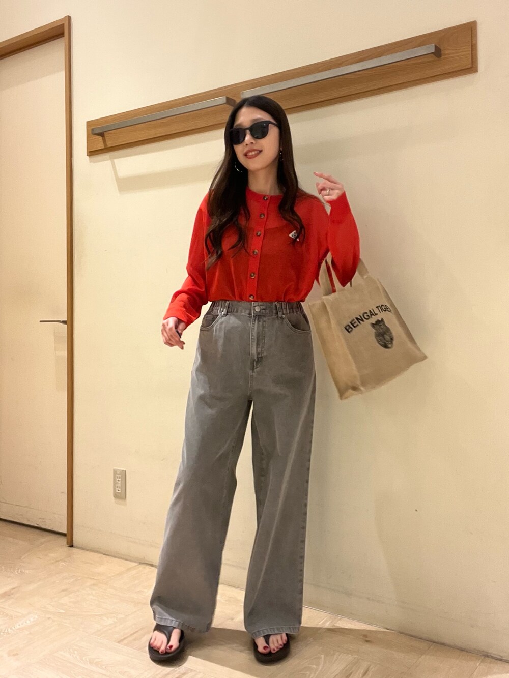 グレー系のデニムパンツ、レッド系のカーディガン/ボレロ、ベージュ系のトートバッグを着用したレディースの春コーディネートの4枚目の写真