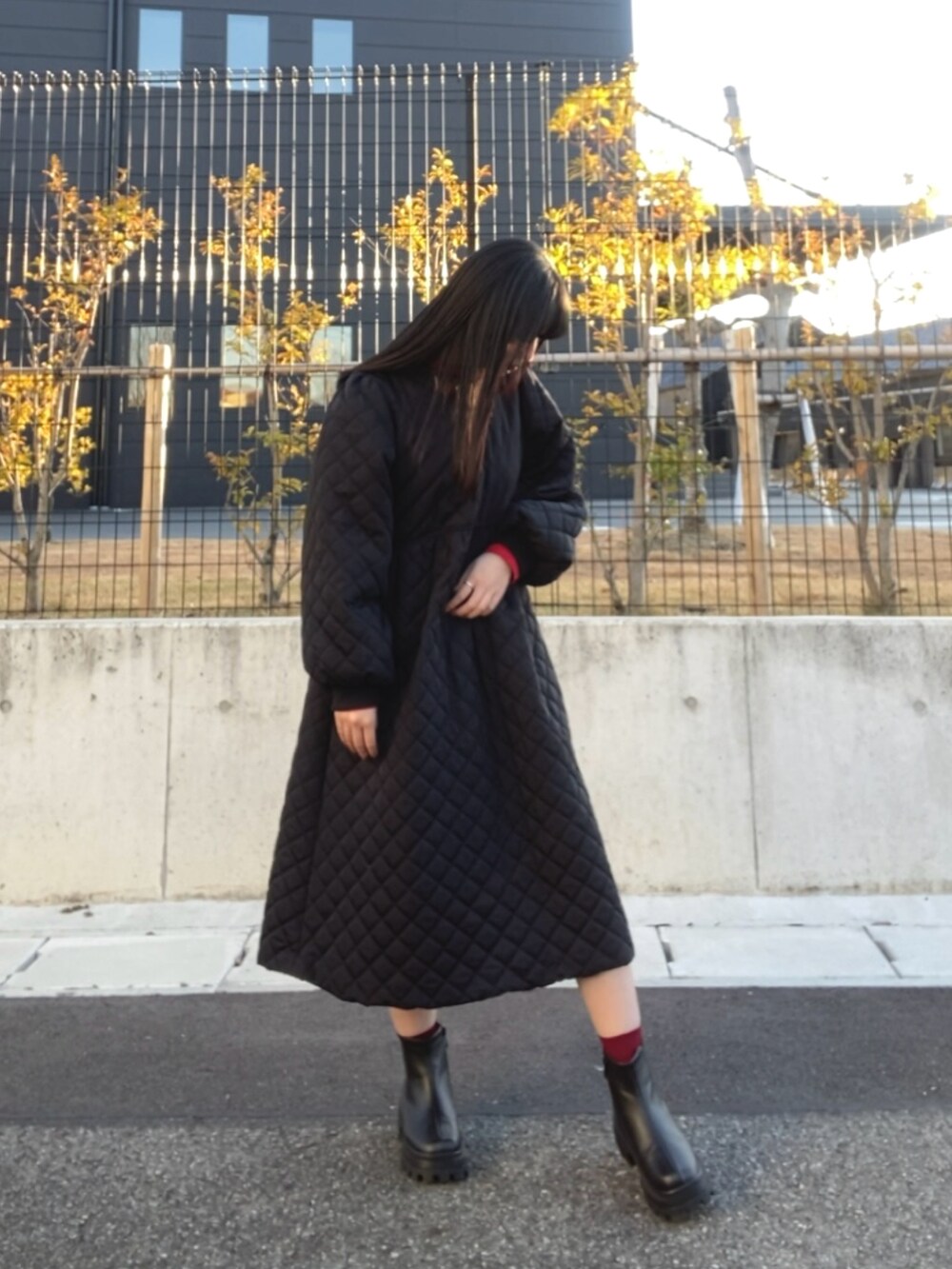 レッド系のニット/セーター、ブラック系のブーツを着用したレディースの冬コーディネートの2枚目の写真