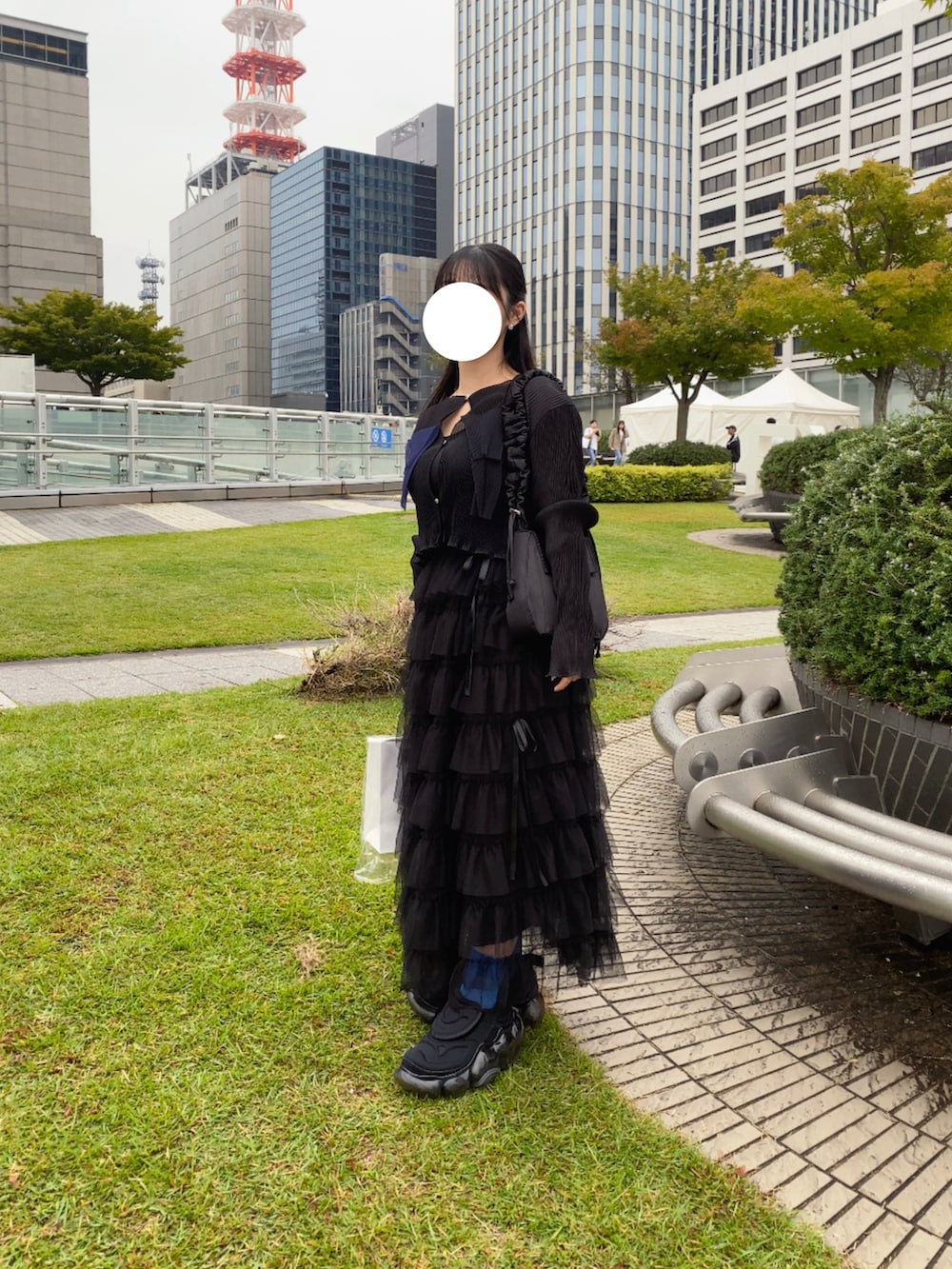 ブラック系のカーディガン/ボレロ、ベージュ系のスカート、ブラック系のスニーカーを着用したレディースの秋コーディネートの2枚目の写真