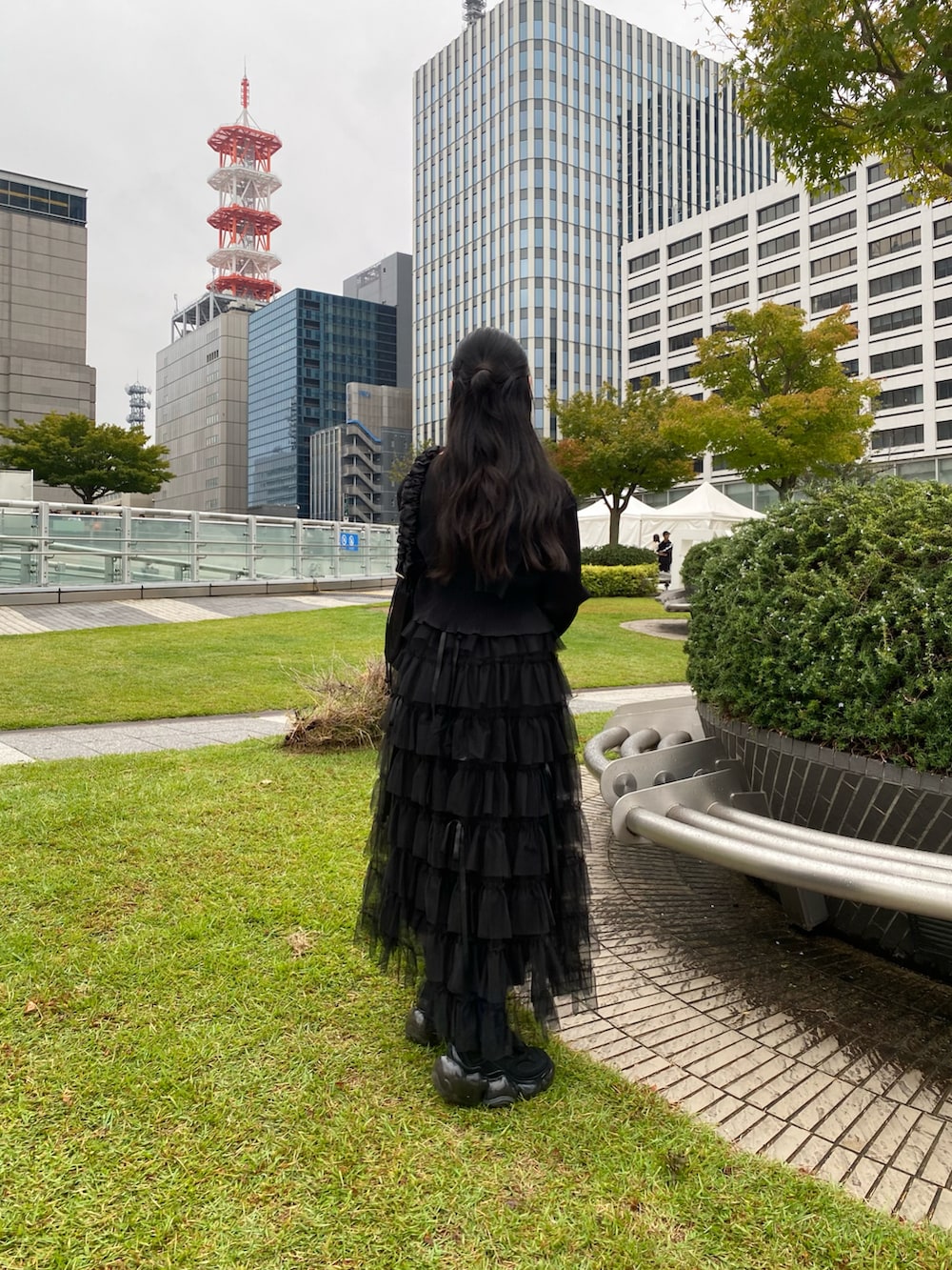 ブラック系のカーディガン/ボレロ、ベージュ系のスカート、ブラック系のスニーカーを着用したレディースの秋コーディネートの4枚目の写真