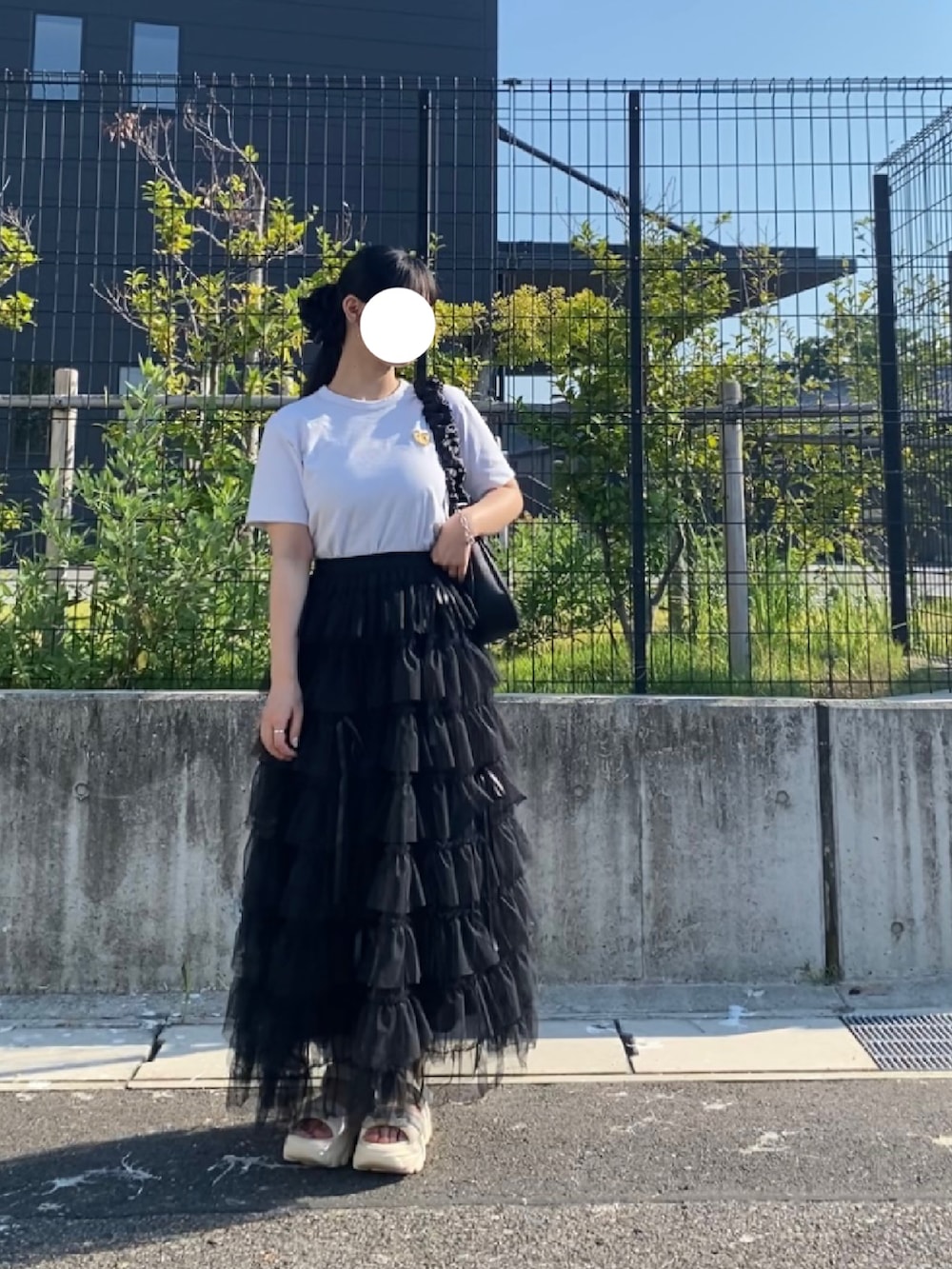 ベージュ系のスカート、ホワイト系のTシャツ/カットソー、ブラック系のバッグを着用したレディースの夏コーディネートの2枚目の写真