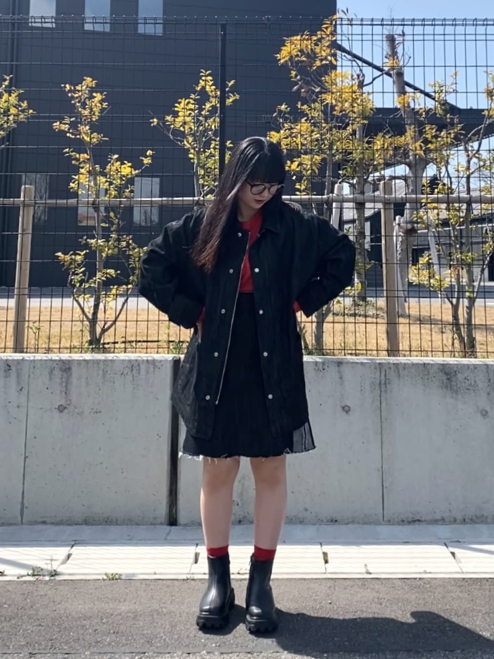 ブラック系のデニムジャケット、ブラック系のデニムスカート、ブラック系のブーツを着用したレディースの春コーディネートの2枚目の写真