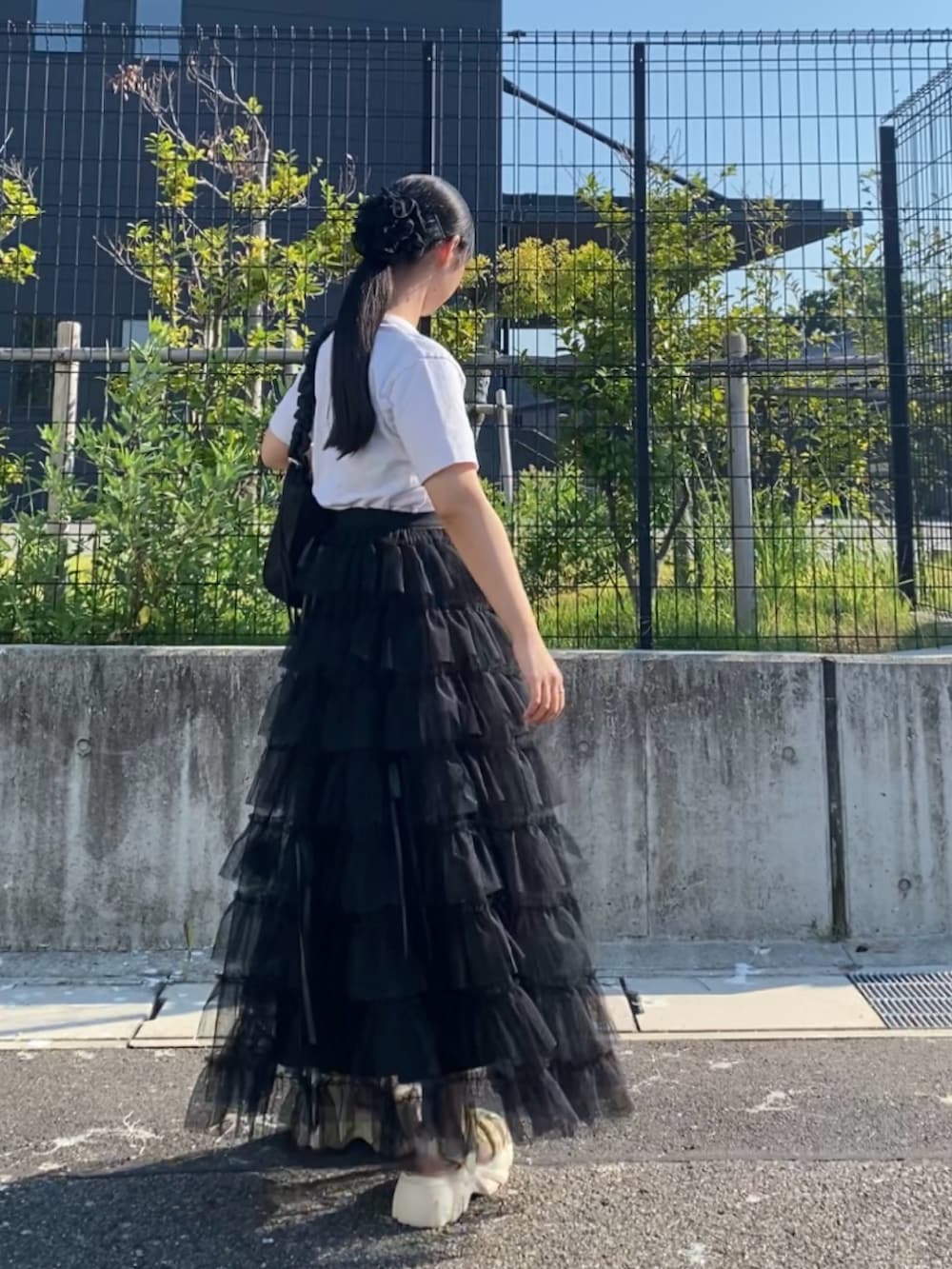 ベージュ系のスカート、ホワイト系のTシャツ/カットソー、ブラック系のバッグを着用したレディースの夏コーディネートの3枚目の写真