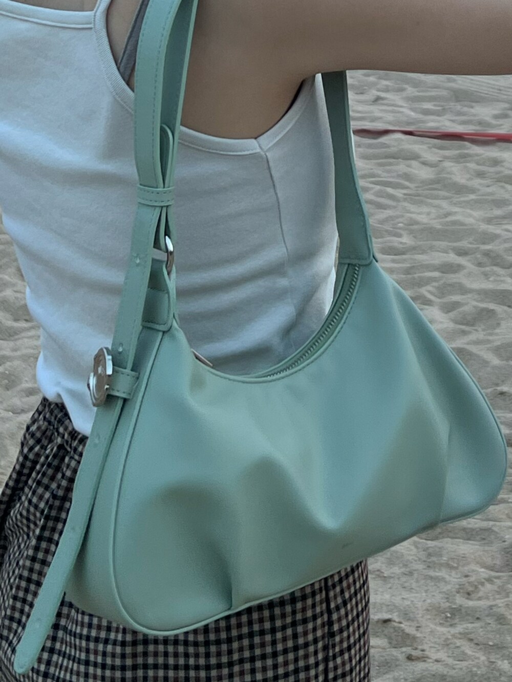 グリーン系のショルダーバッグ、ブラック系のトップスを着用したレディースの秋コーディネートの4枚目の写真