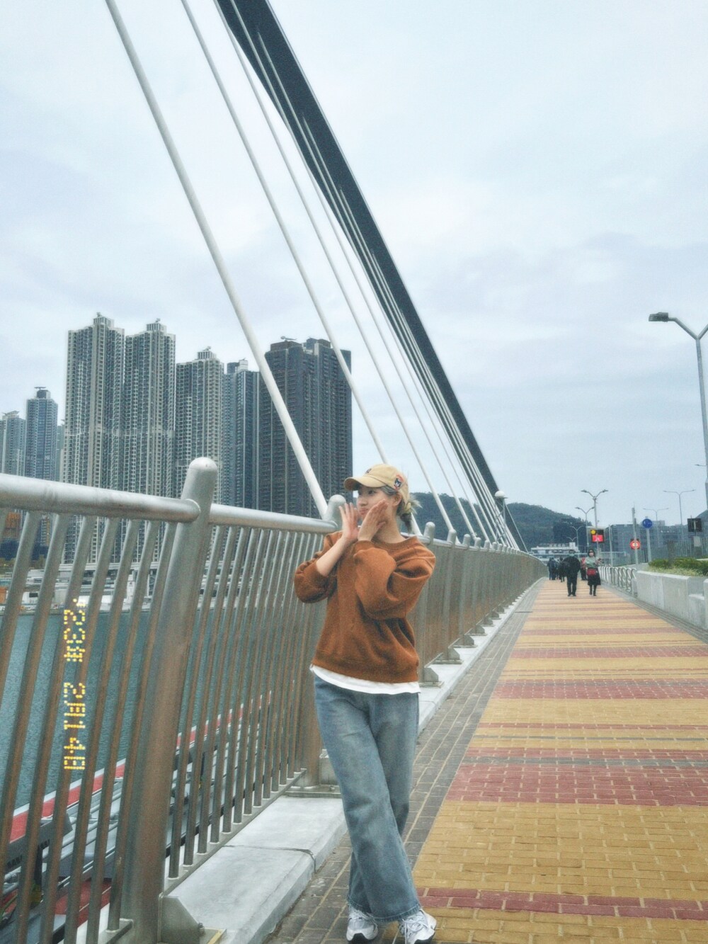 ホワイト系のスニーカー、グリーン系のショルダーバッグ、ベージュ系のキャップを着用したレディースの冬コーディネートの2枚目の写真