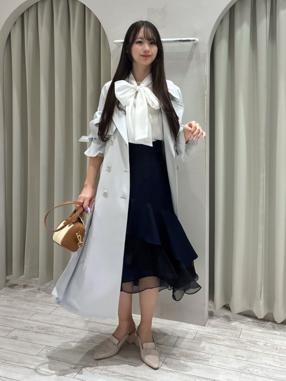 ホワイト系のパンプス、ホワイト系のシャツ/ブラウス、ブラウン系のハンドバッグを着用したレディースの春コーディネートの3枚目の写真