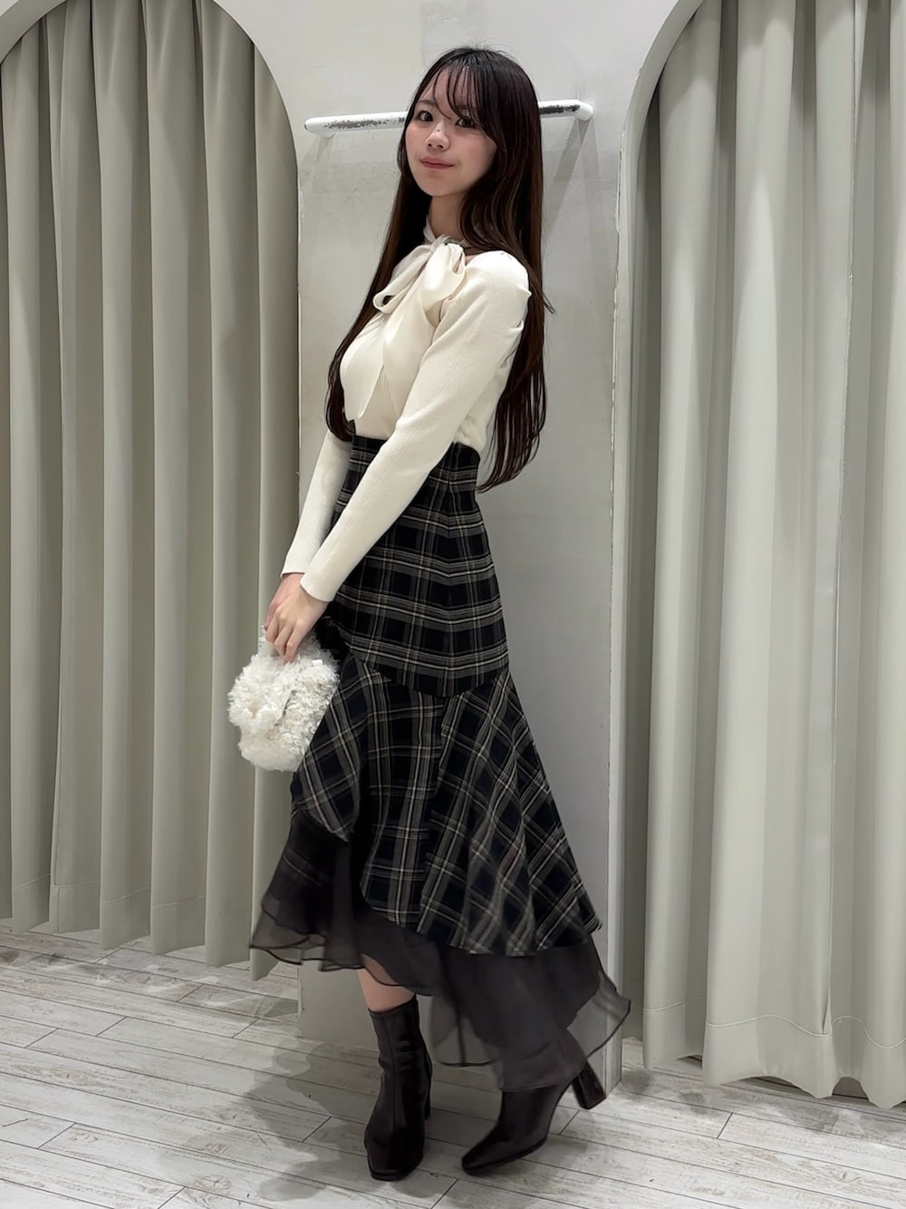 ホワイト系のニット/セーター、グレー系のスカート、ホワイト系のハンドバッグを着用したレディースの冬コーディネートの3枚目の写真