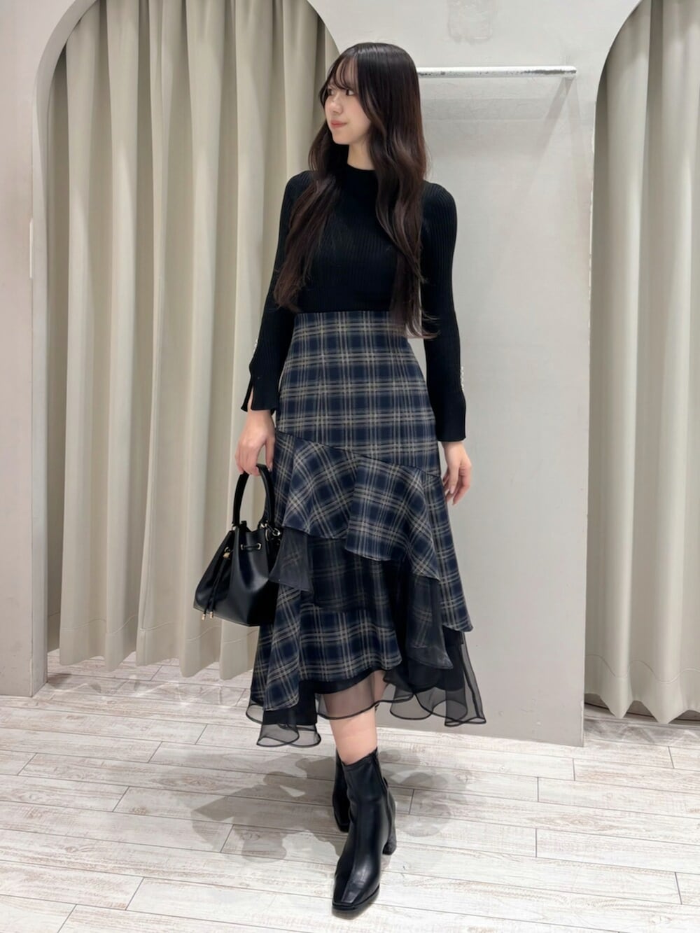 ブラック系のショルダーバッグ、ブラック系のニット/セーター、ブルー系のスカートを着用したレディースの冬コーディネートの4枚目の写真