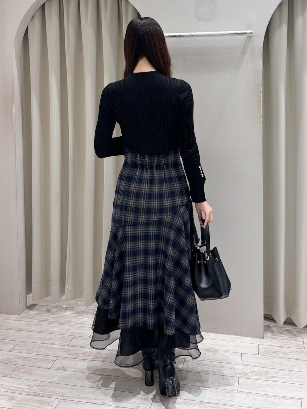 ブラック系のショルダーバッグ、ブラック系のニット/セーター、ブルー系のスカートを着用したレディースの冬コーディネートの6枚目の写真