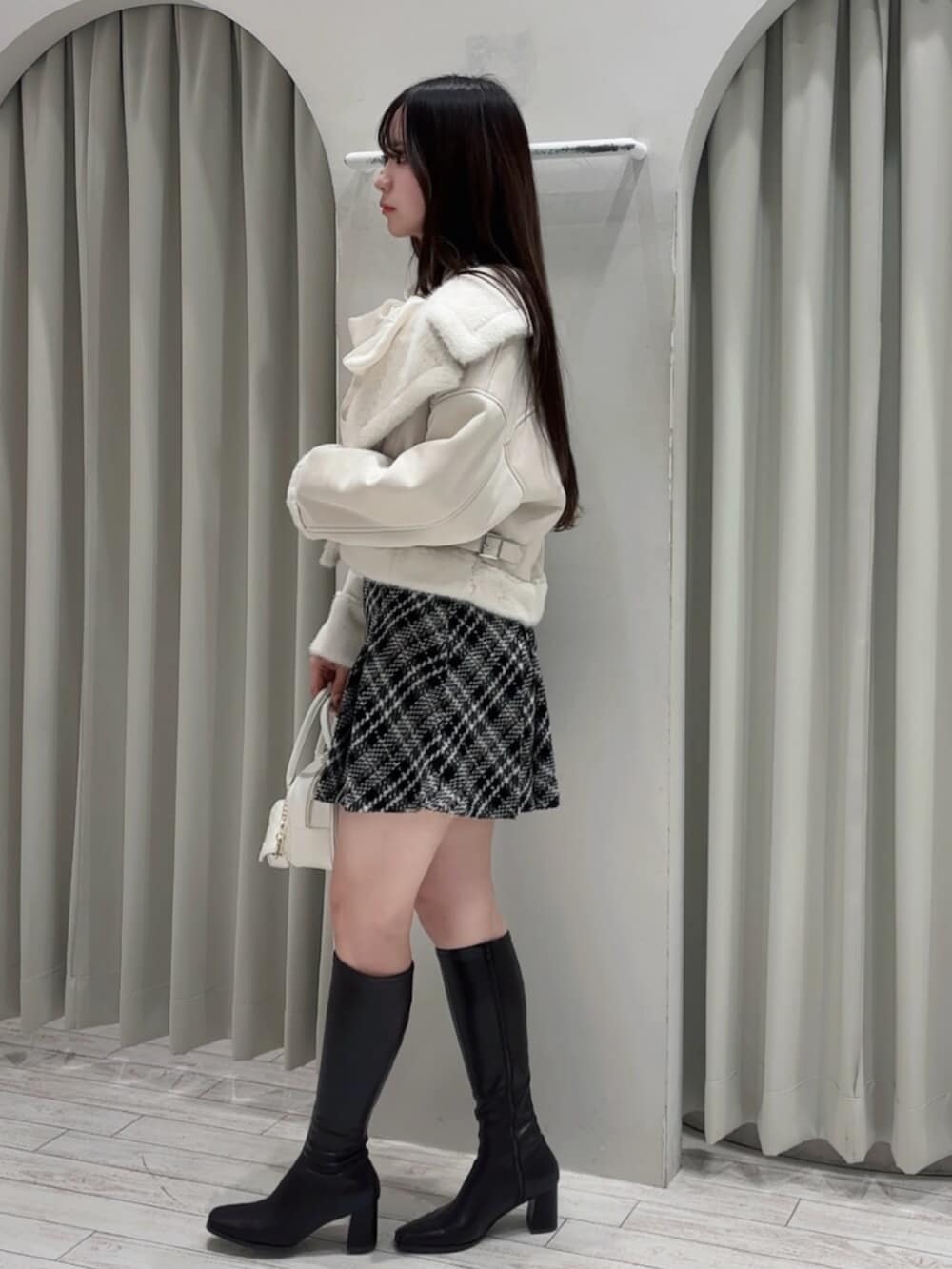 ホワイト系のハンドバッグ、ホワイト系のムートンコート、ブラック系のその他パンツを着用したレディースの秋コーディネートの4枚目の写真