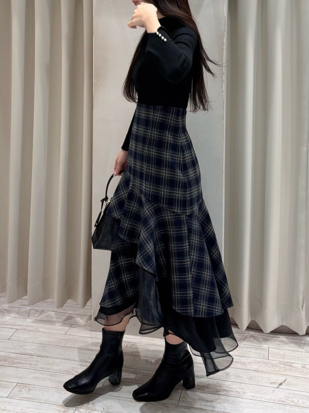 ブラック系のショルダーバッグ、ブラック系のニット/セーター、ブルー系のスカートを着用したレディースの冬コーディネートの8枚目の写真