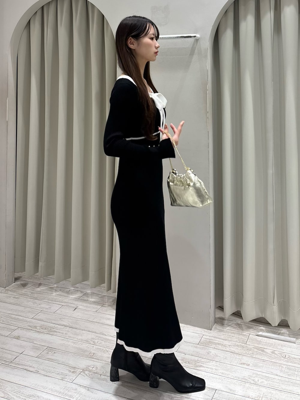 ブラック系のワンピース、ゴールド系のショルダーバッグ、ブラック系のブーツを着用したレディースの冬コーディネートの4枚目の写真