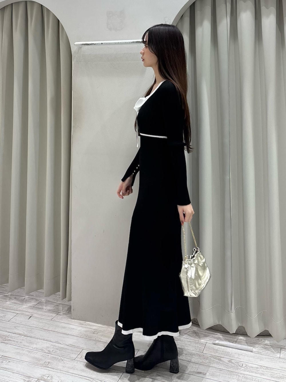 ブラック系のワンピース、ゴールド系のショルダーバッグ、ブラック系のブーツを着用したレディースの冬コーディネートの3枚目の写真