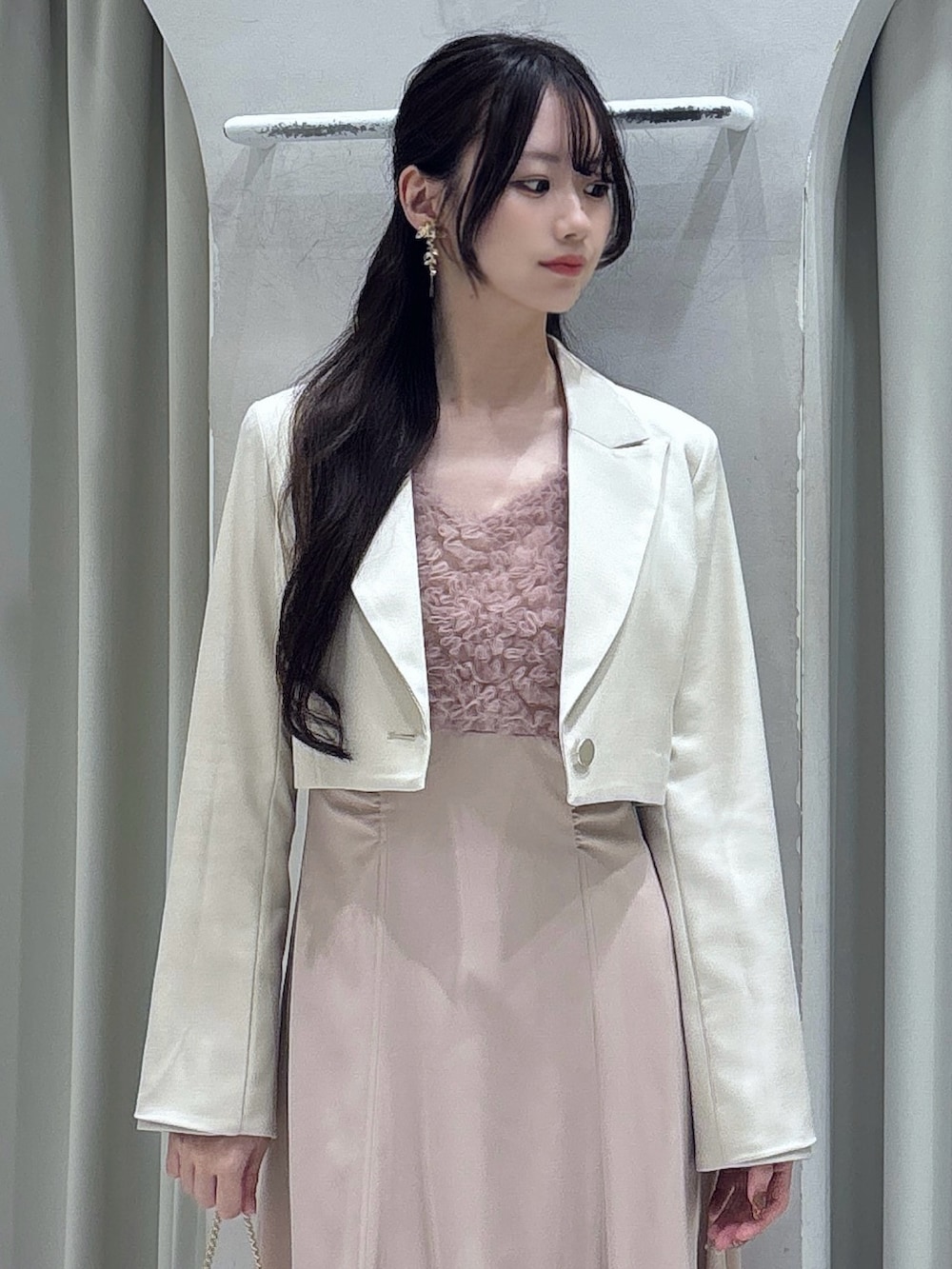 ピンク系のドレス、ホワイト系のテーラードジャケット、ゴールド系のショルダーバッグを着用したレディースの春コーディネートの6枚目の写真