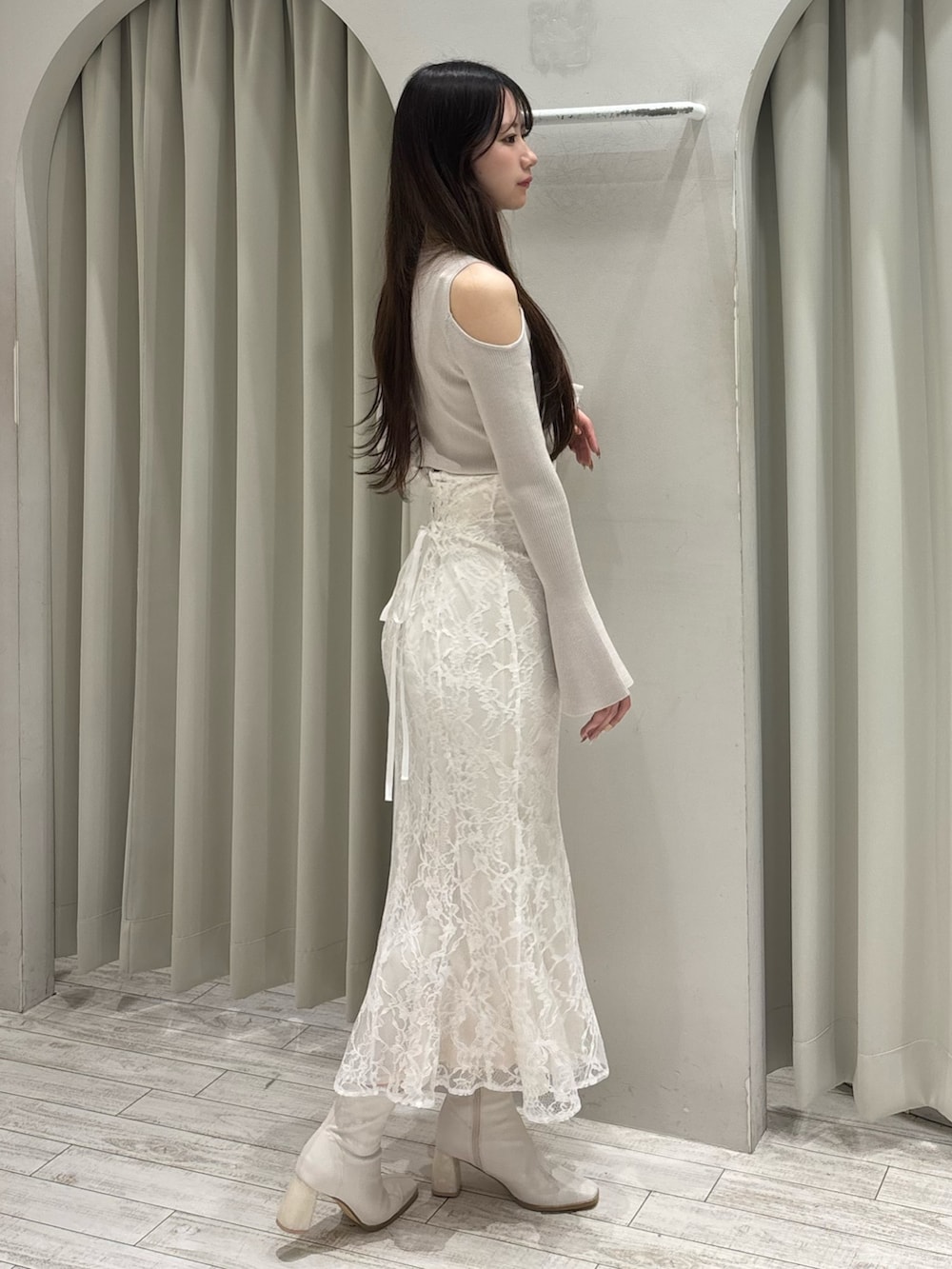 ベージュ系のニット/セーター、ホワイト系のスカート、ホワイト系のブーツを着用したレディースの春コーディネートの4枚目の写真