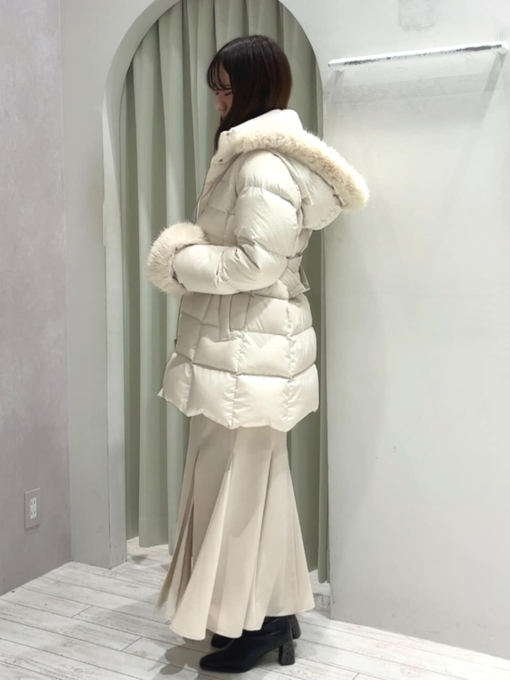 ホワイト系のハンドバッグ、ブラック系のブーツ、ホワイト系のダウンジャケット/コートを着用したレディースの秋コーディネートの5枚目の写真