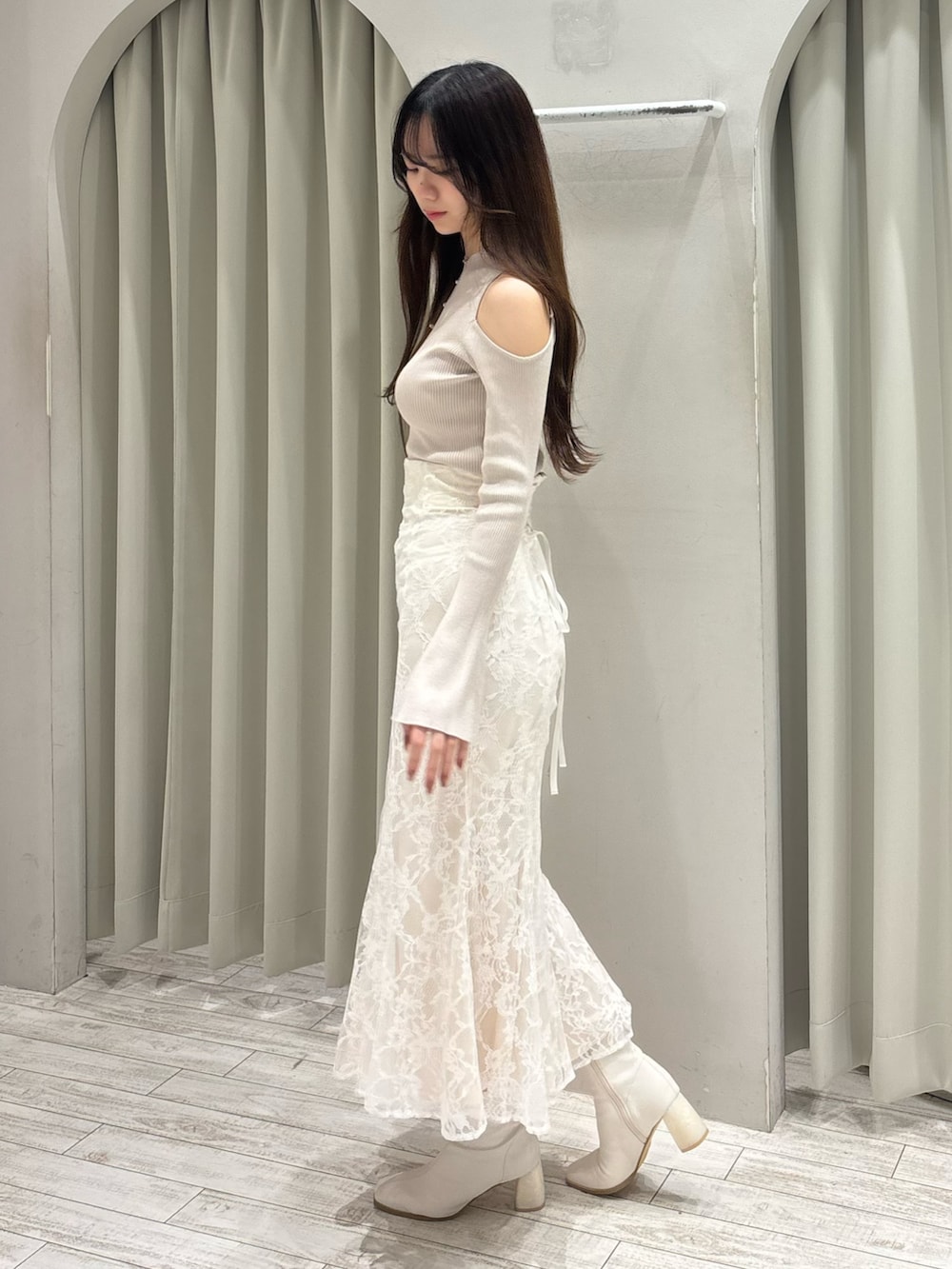 ベージュ系のニット/セーター、ホワイト系のスカート、ホワイト系のブーツを着用したレディースの春コーディネートの3枚目の写真