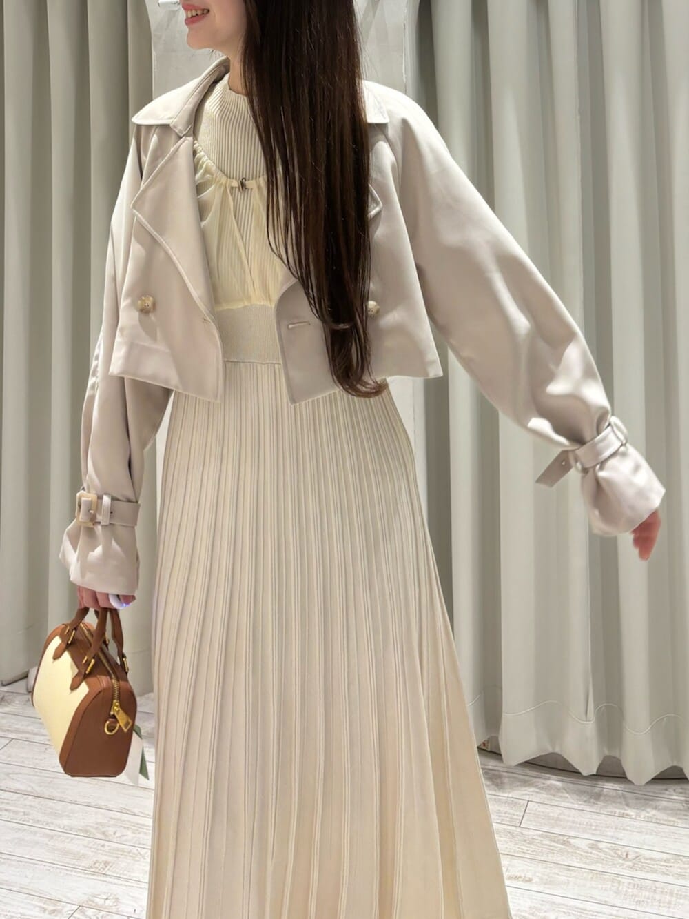 ブラウン系のハンドバッグ、ホワイト系のパンプス、ベージュ系のトレンチコートを着用したレディースの春コーディネートの7枚目の写真