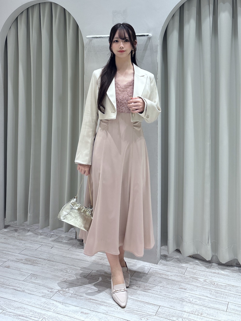 ピンク系のドレス、ホワイト系のテーラードジャケット、ゴールド系のショルダーバッグを着用したレディースの春コーディネートの2枚目の写真