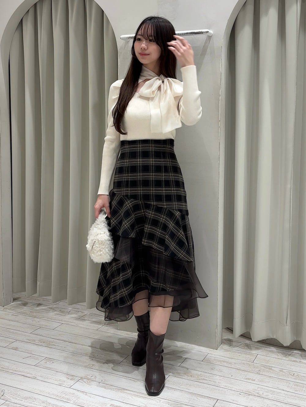 ホワイト系のニット/セーター、グレー系のスカート、ホワイト系のハンドバッグを着用したレディースの冬コーディネートの2枚目の写真