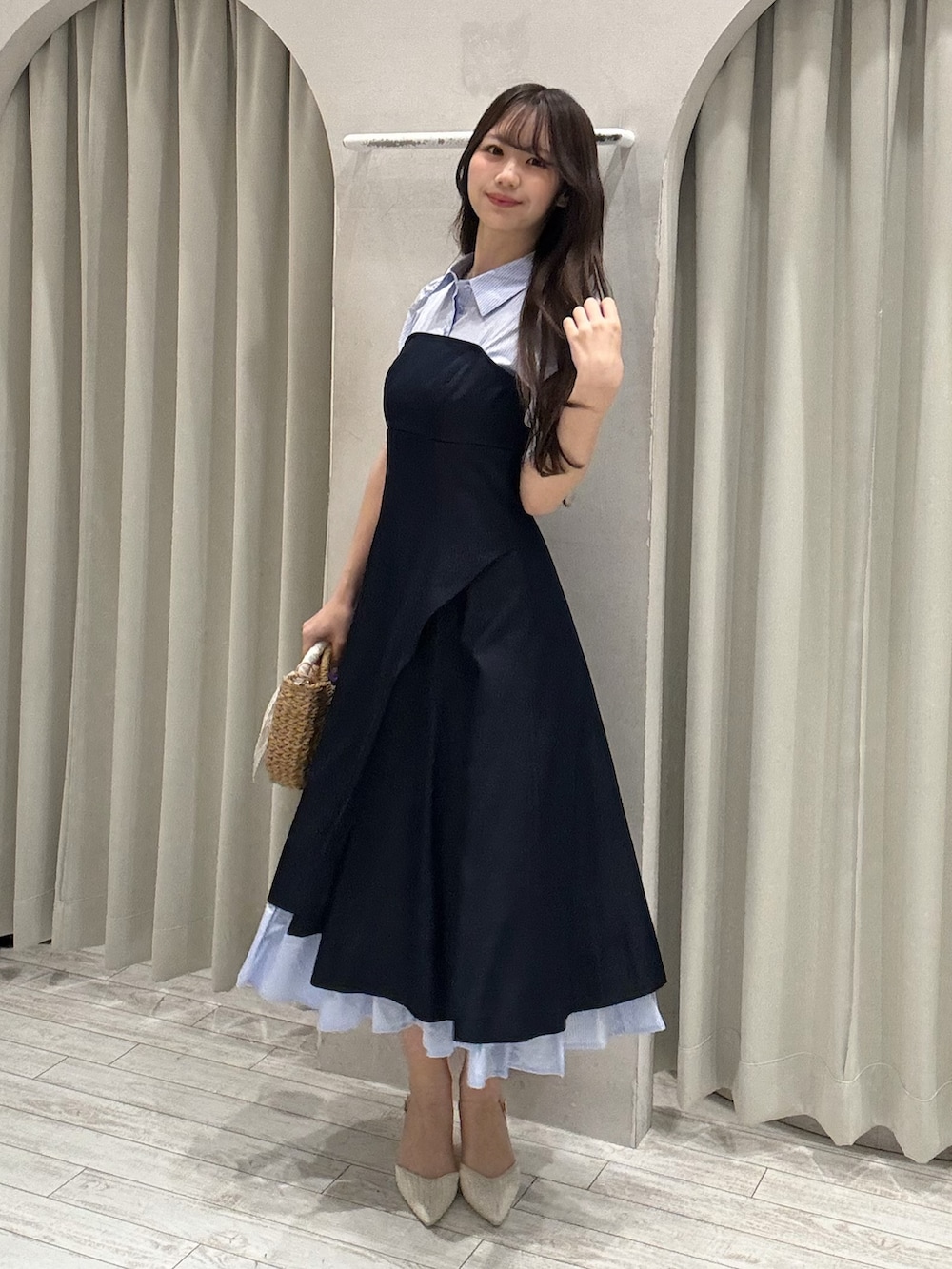 ブルー系のワンピース、ベージュ系のハンドバッグ、ホワイト系のパンプスを着用したレディースの春コーディネートの2枚目の写真